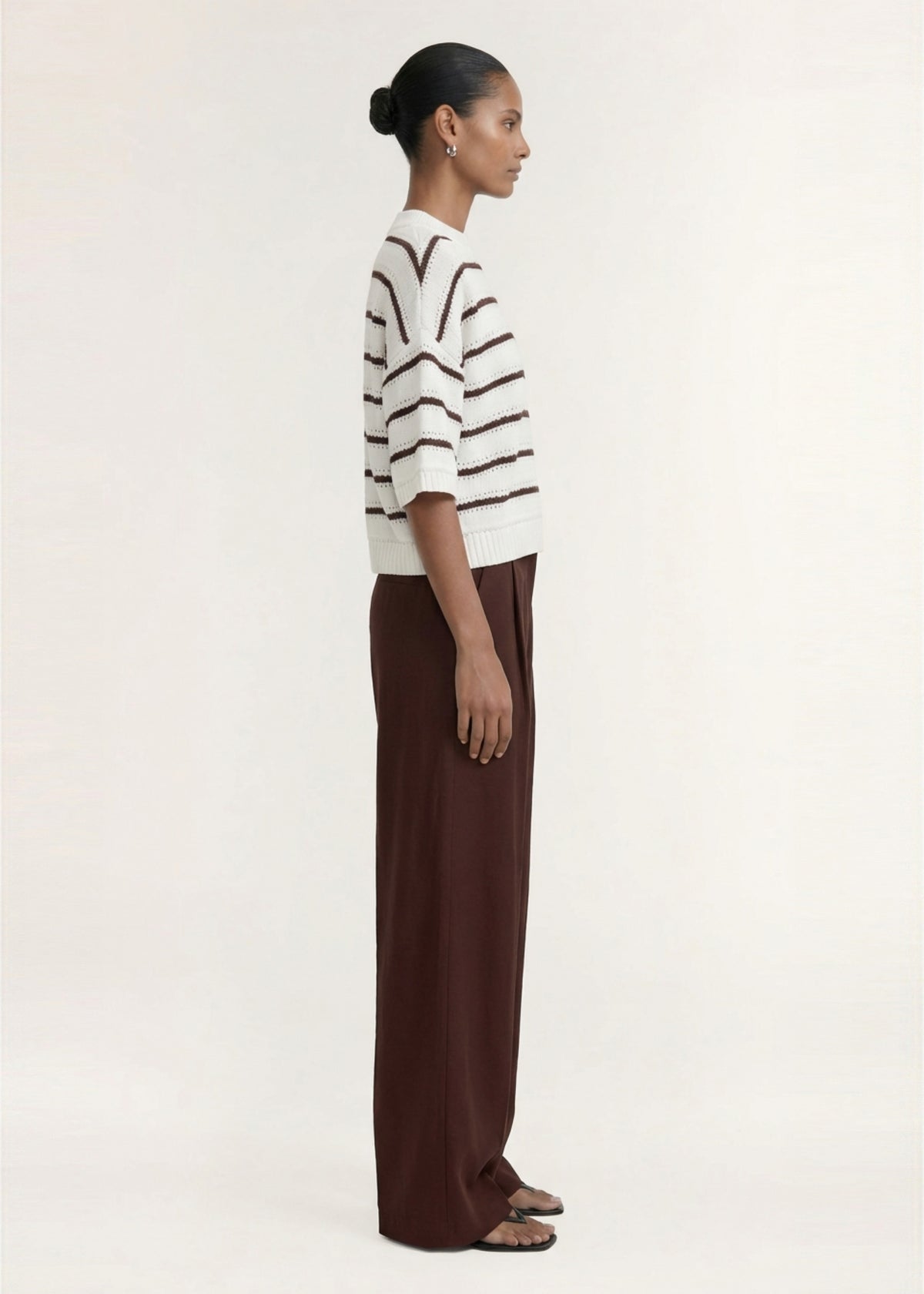 Angled view of the Brown Stripe Cotton Blend Crew Knit Tee with a round neckline and dropped shoulders.
