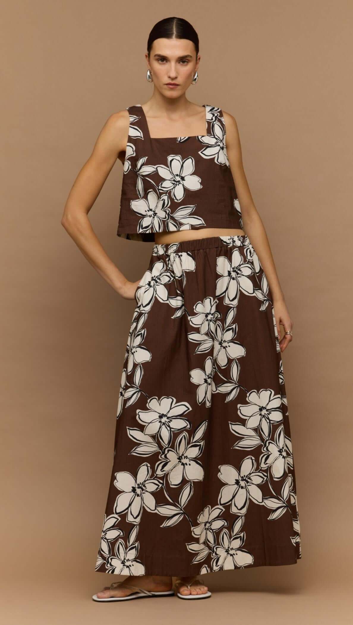 Model wearing a brown and white floral A-line maxi skirt paired with a matching crop top against a neutral background.