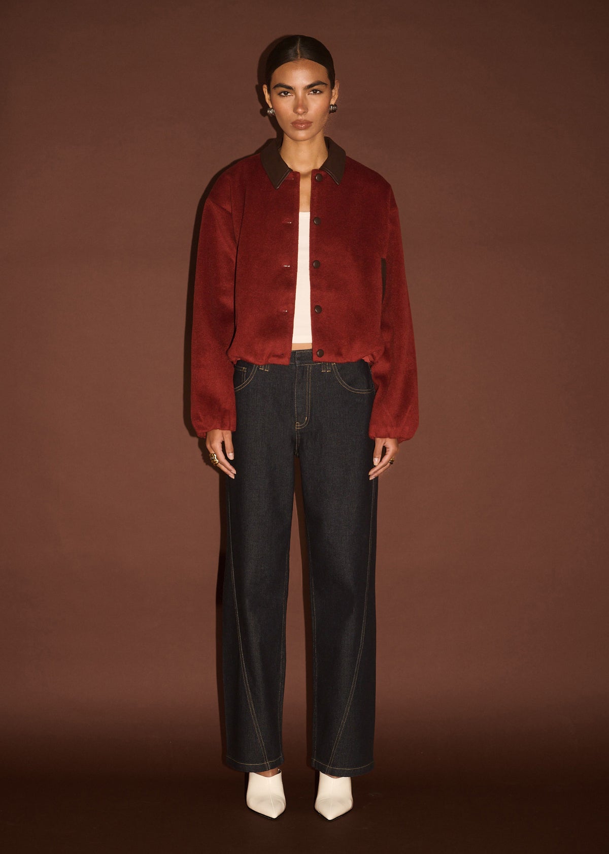 Model wearing Burgundy Brushed Bomber Jacket, showing a cropped length and a relaxed fit, photographed against a brown studio backdrop.