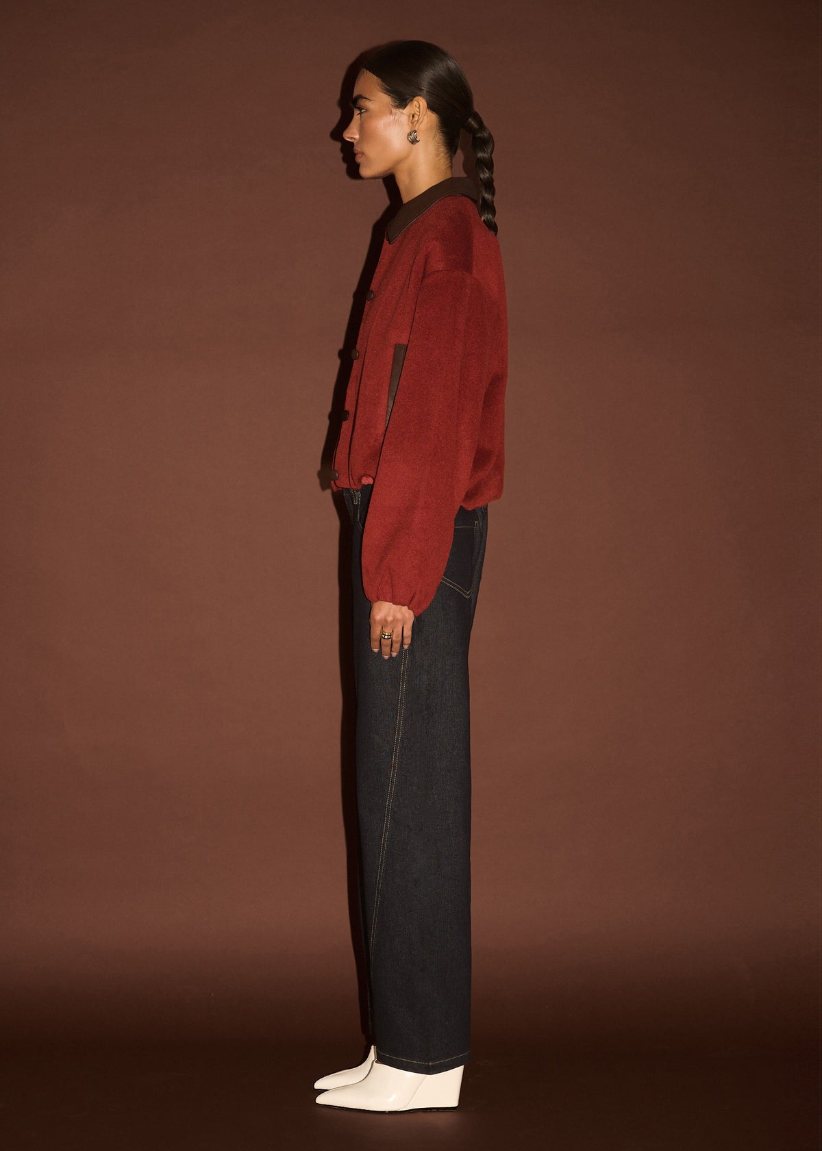 Side view of the Burgundy Brushed Bomber Jacket, showing an elasticated cuffs and hem, photographed against a brown studio backdrop.