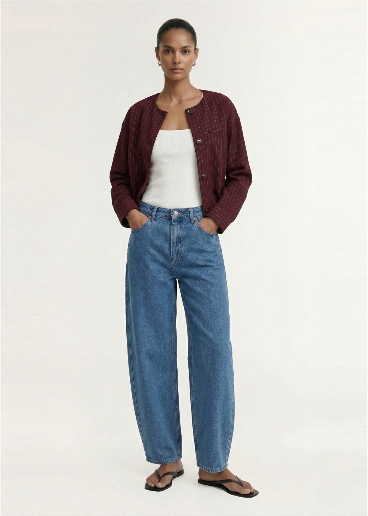 Model wearing Burgundy Pinstripe Cropped Jacket with a cropped silhouette and a pinstripe fabrication.