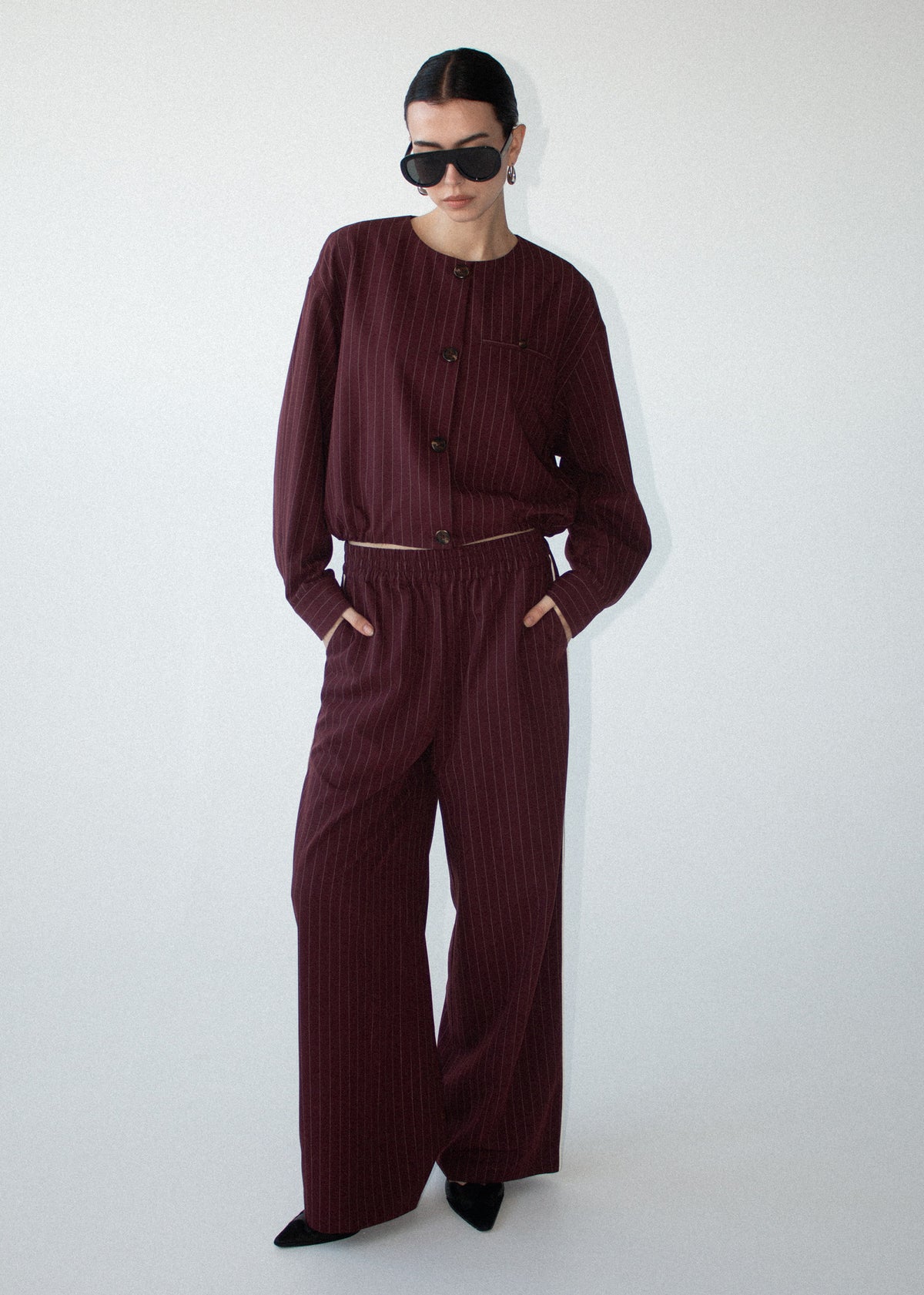 Model wearing Burgundy Pinstripe Cropped Jacket with a pinstripe fabrication and a cropped silhouette.