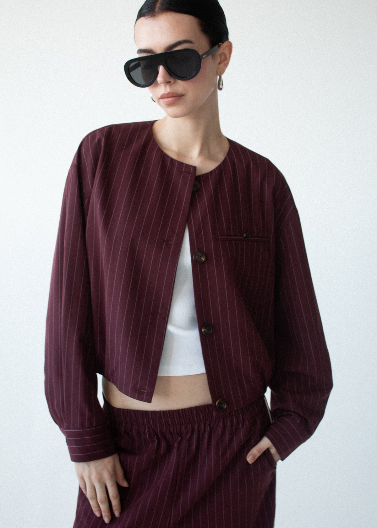 Close-up of Burgundy Pinstripe Cropped Jacket with a collarless neckline and a front button closure.