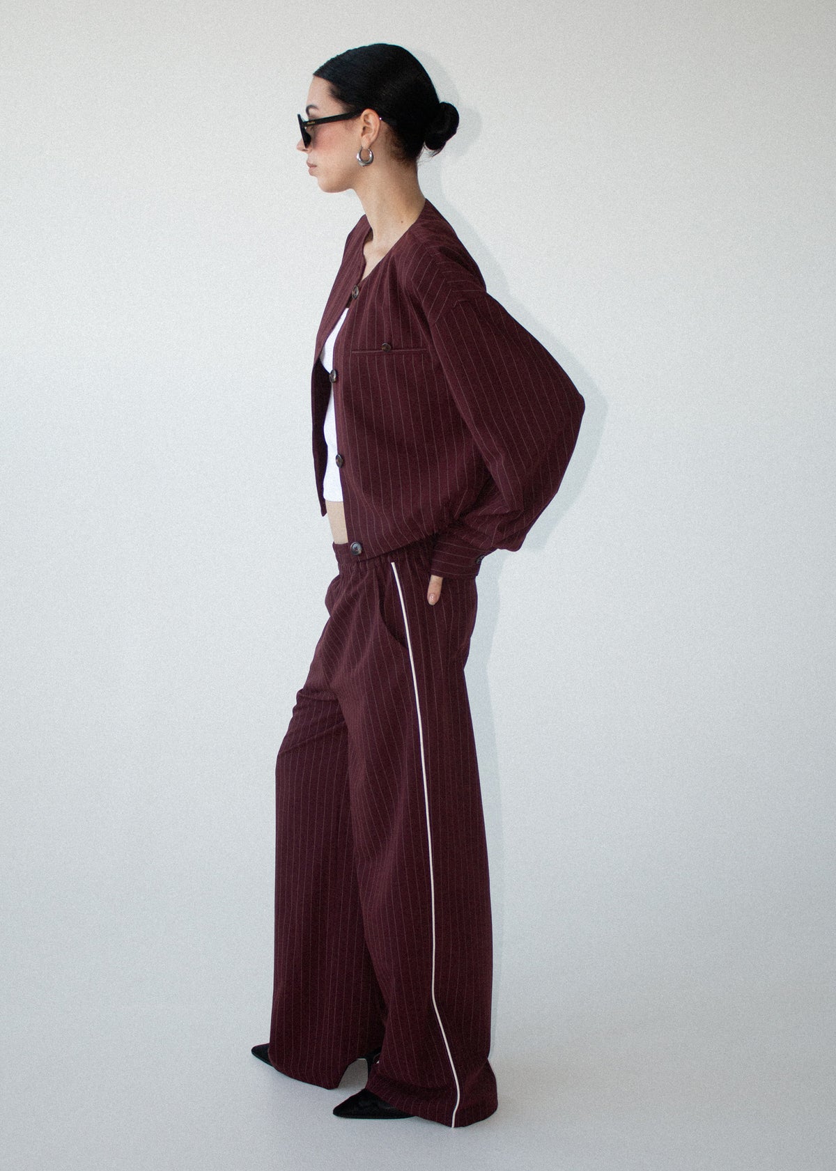 Side view of the Burgundy Pinstripe Cropped Jacket, showing full length sleeves and a front welt pocket detailing.