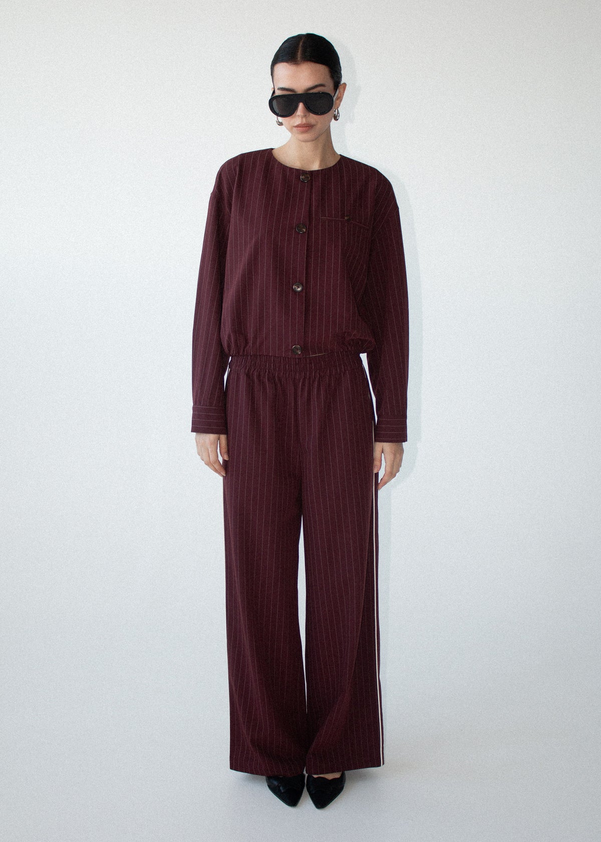 Model wearing Burgundy Pinstripe Relaxed Pant, showing a pinstripe design and a relaxed straight-leg silhouette.