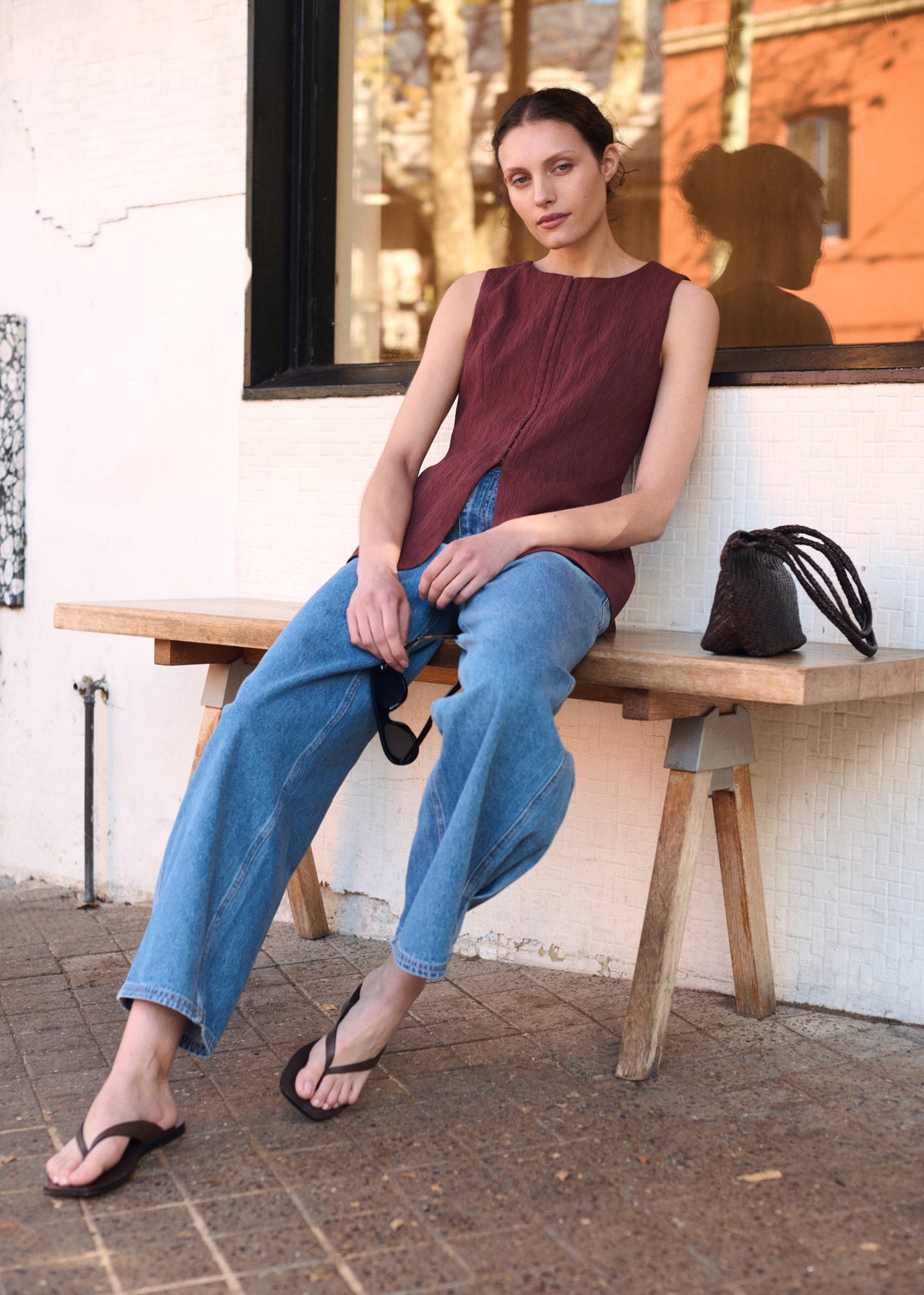 Model seated wearing Burgundy Round Neck Textured Vest with a relaxed tailored fit and a fully lined, photographed at wooden bench outdoors.