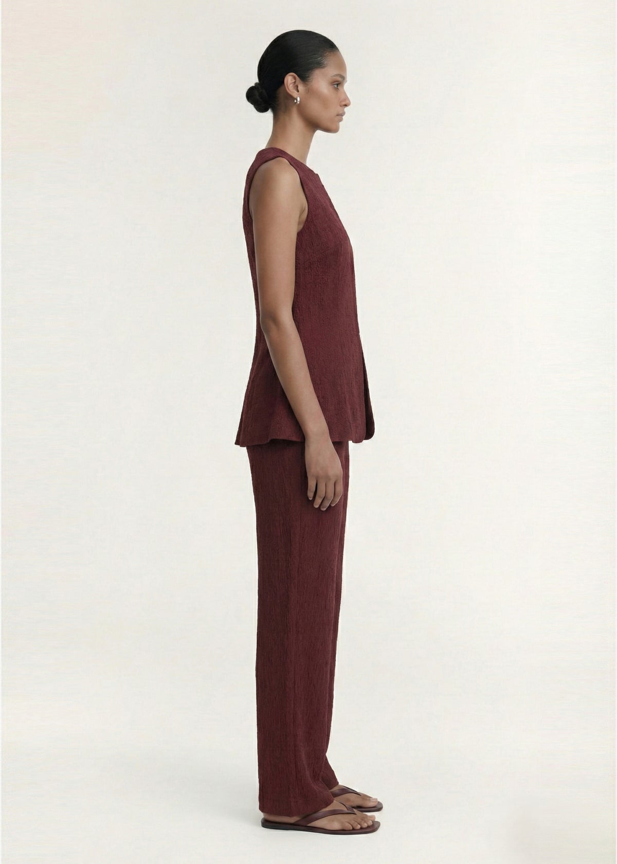 Side view of the Burgundy Round Neck Textured Vest, showing a concealed front closure and a shaped waist detailing.
