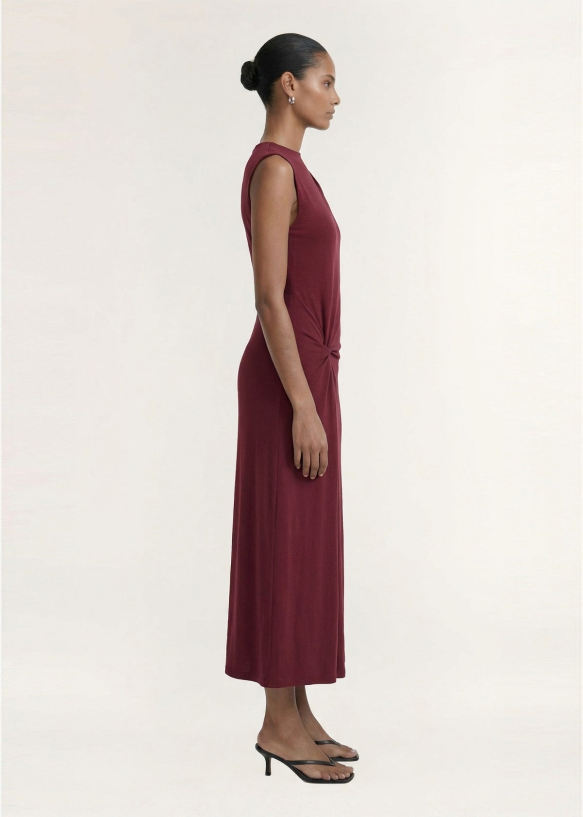 Side view of the Burgundy Twist Detail Jersey Midi Dress, showing a slim fit through bodice and an invisible back zip closure.