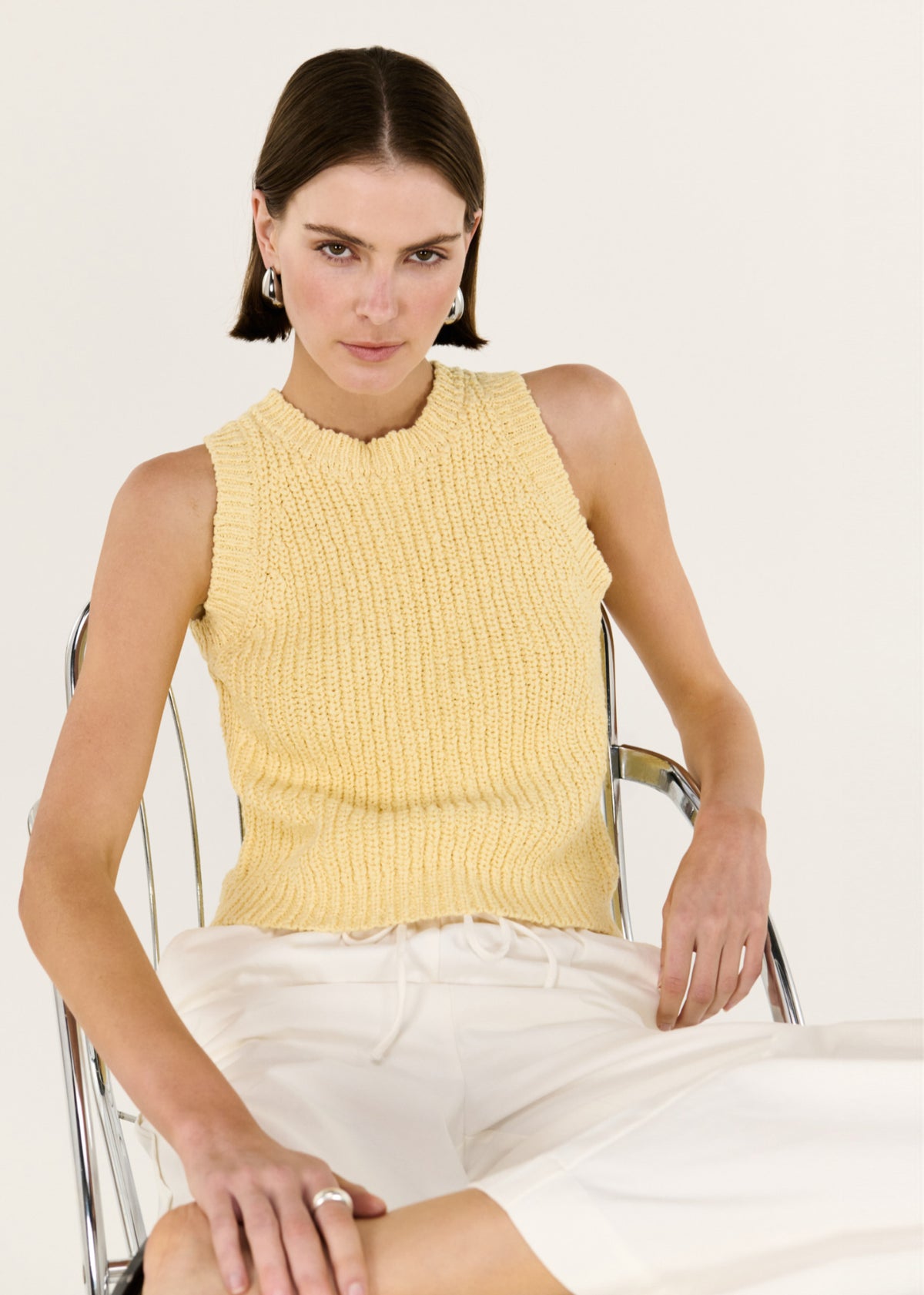 Model seated wearing Butter Yellow Cotton Blend Knit Tank with a softly textured cotton-blend knit and a relaxed yet refined fit.