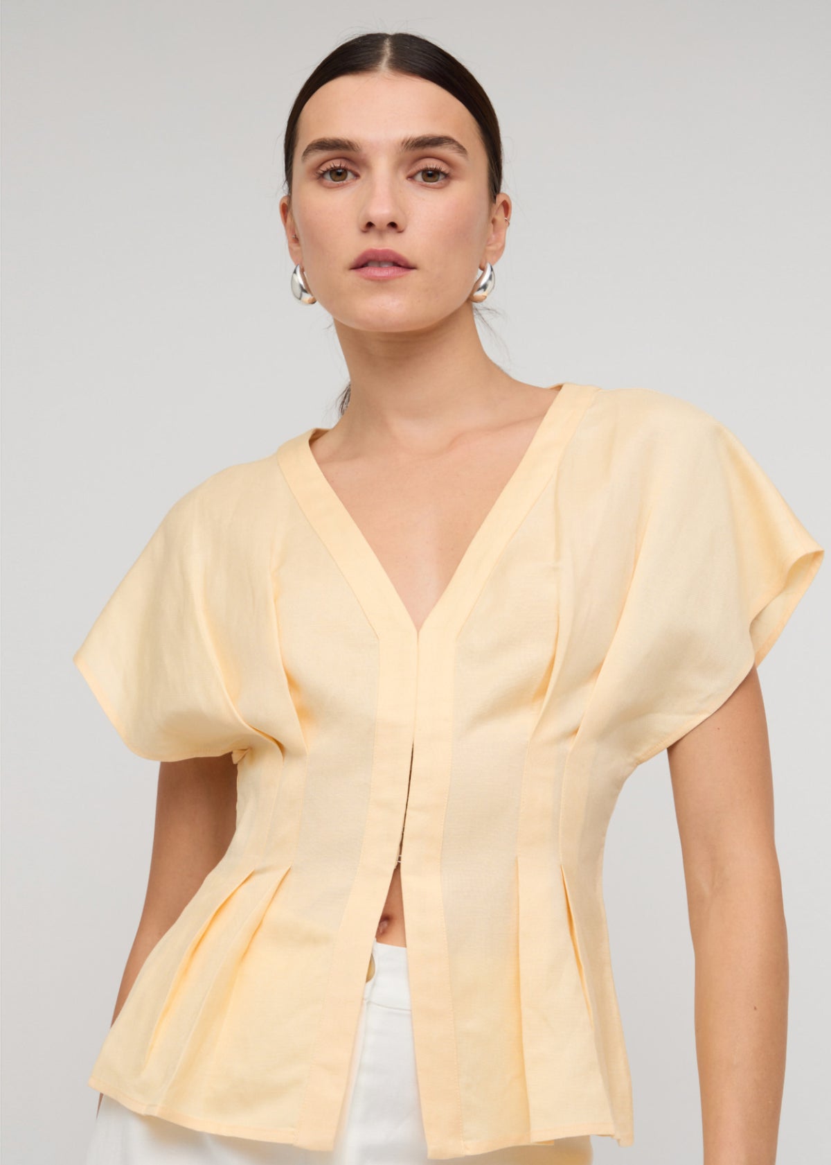 Close-up of the Butter Yellow Linen Pleated Blouse, showing a deep V-neckline and a soft butter yellow shade.