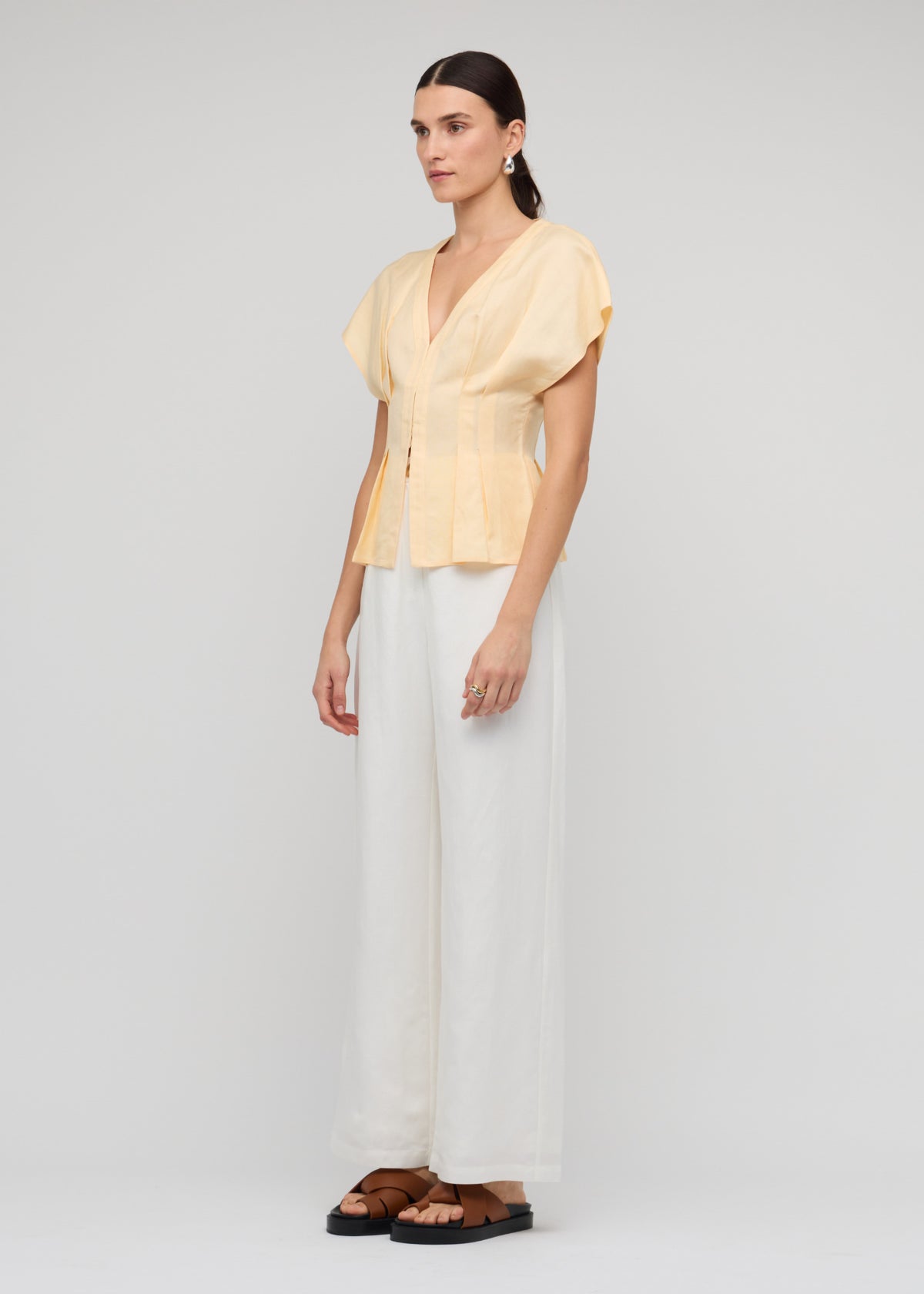 Model wearing Butter Yellow Linen Pleated Blouse, showing a soft butter yellow shade and a deep V-neckline.