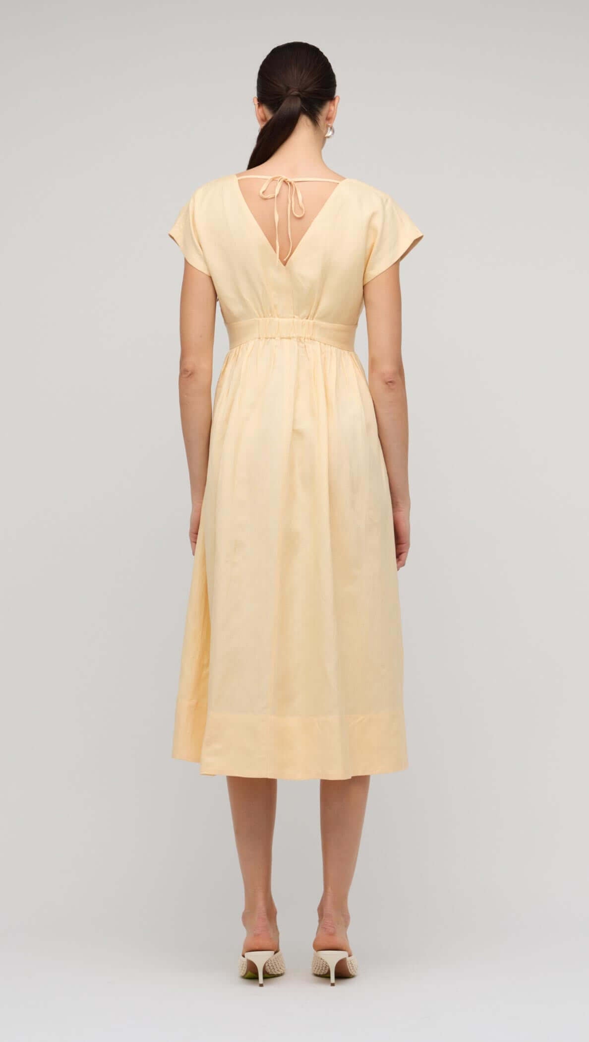 Back view of the Butter Yellow Linen V-Neck Midi Dress showcasing the V-back and flowing design.
