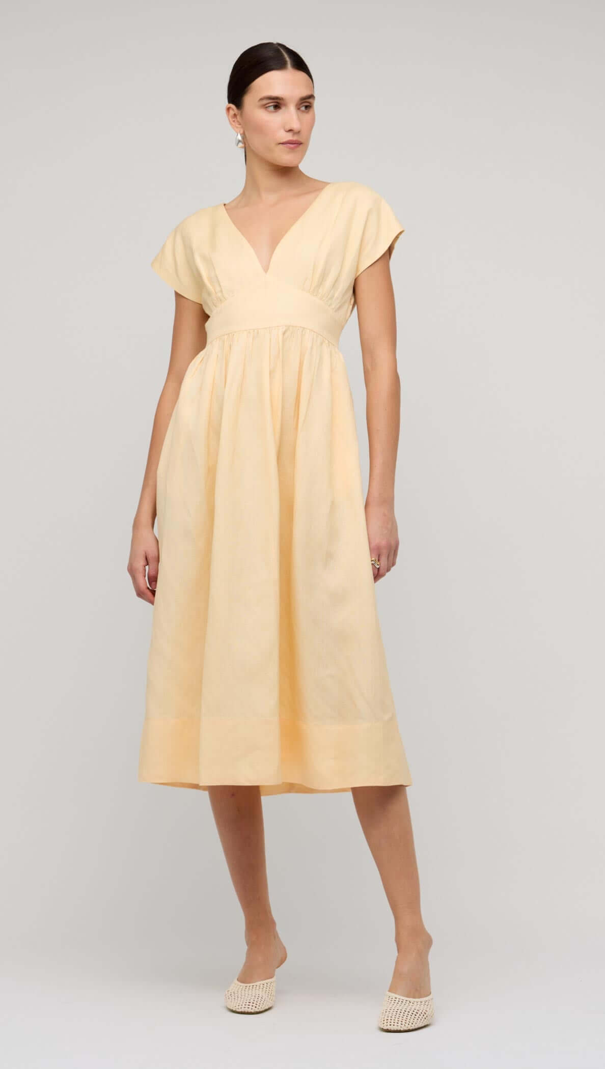 Butter Yellow Linen V-Neck Midi Dress worn by a model, showcasing its elegant design and flattering silhouette.