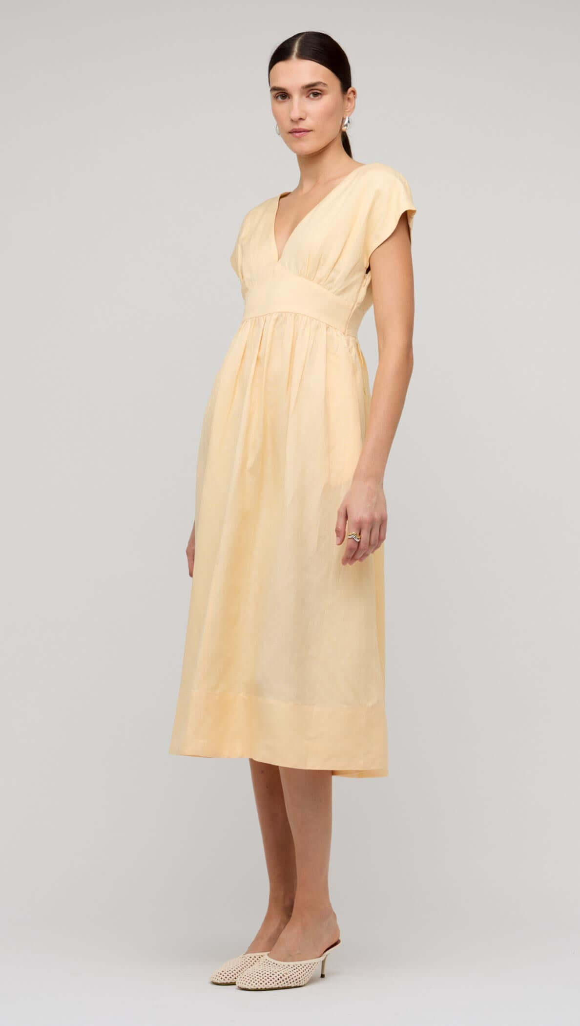 Butter Yellow Linen V-Neck Midi Dress model wearing a soft pastel yellow dress with a deep V-neckline and flowing skirt.