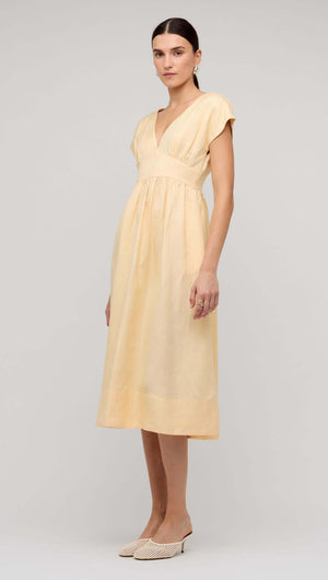 Butter Yellow Linen V-Neck Midi Dress model wearing a soft pastel yellow dress with a deep V-neckline and flowing skirt.