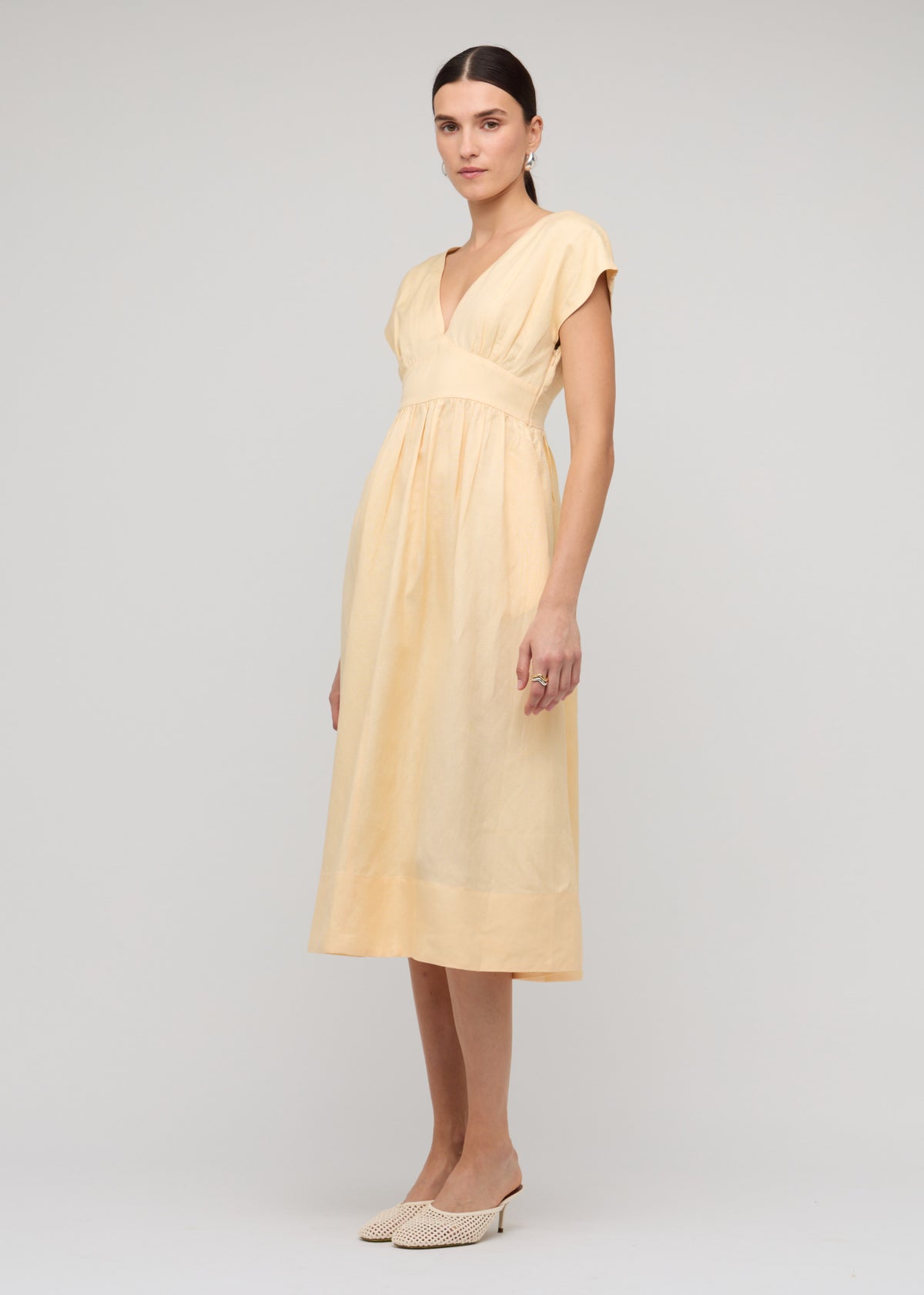Model wearing Butter Yellow Linen V-Neck Midi Dress, showing deep V-neckline with cap sleeves.