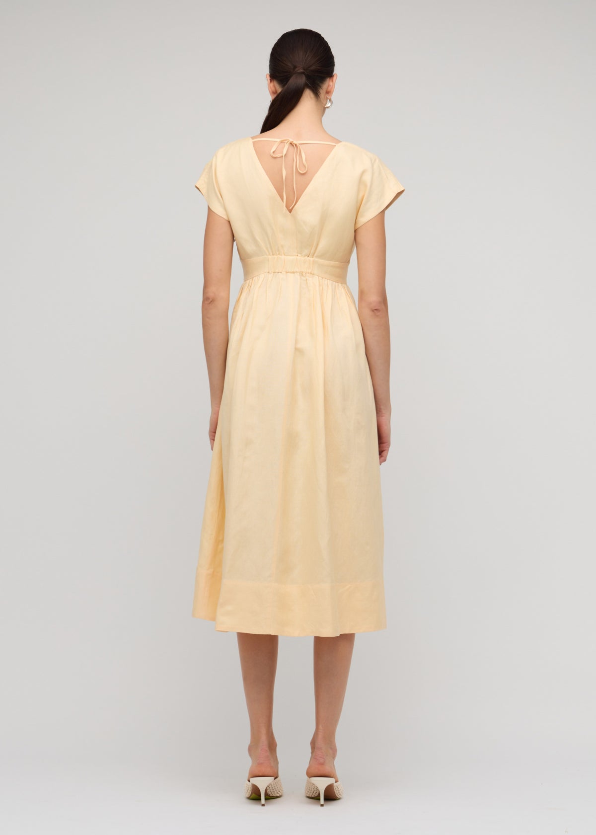 Back view of the Butter Yellow Linen V-Neck Midi Dress with a back tie detail with subtle elastic waist and a soft pastel yellow tone.
