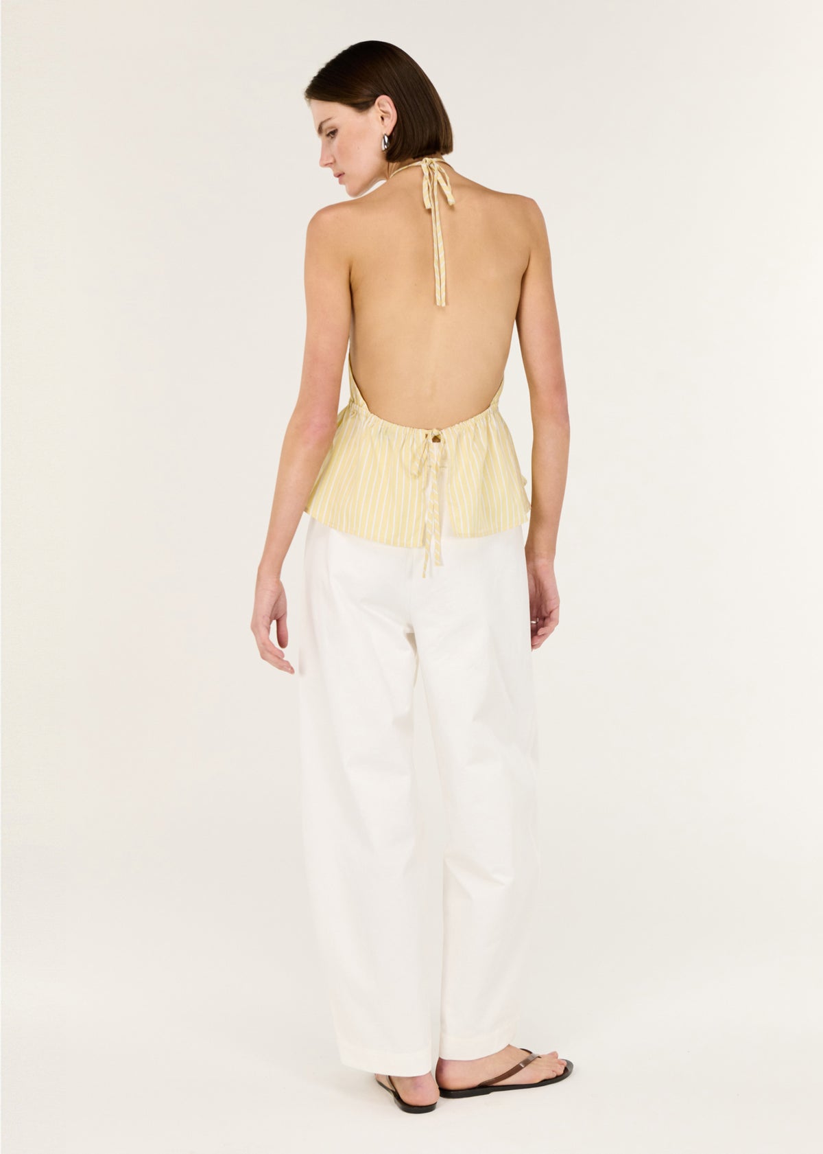 Back view of the Butter Yellow Low Back Striped Halter Top, showing a halter neckline with adjustable tie and an open back design.