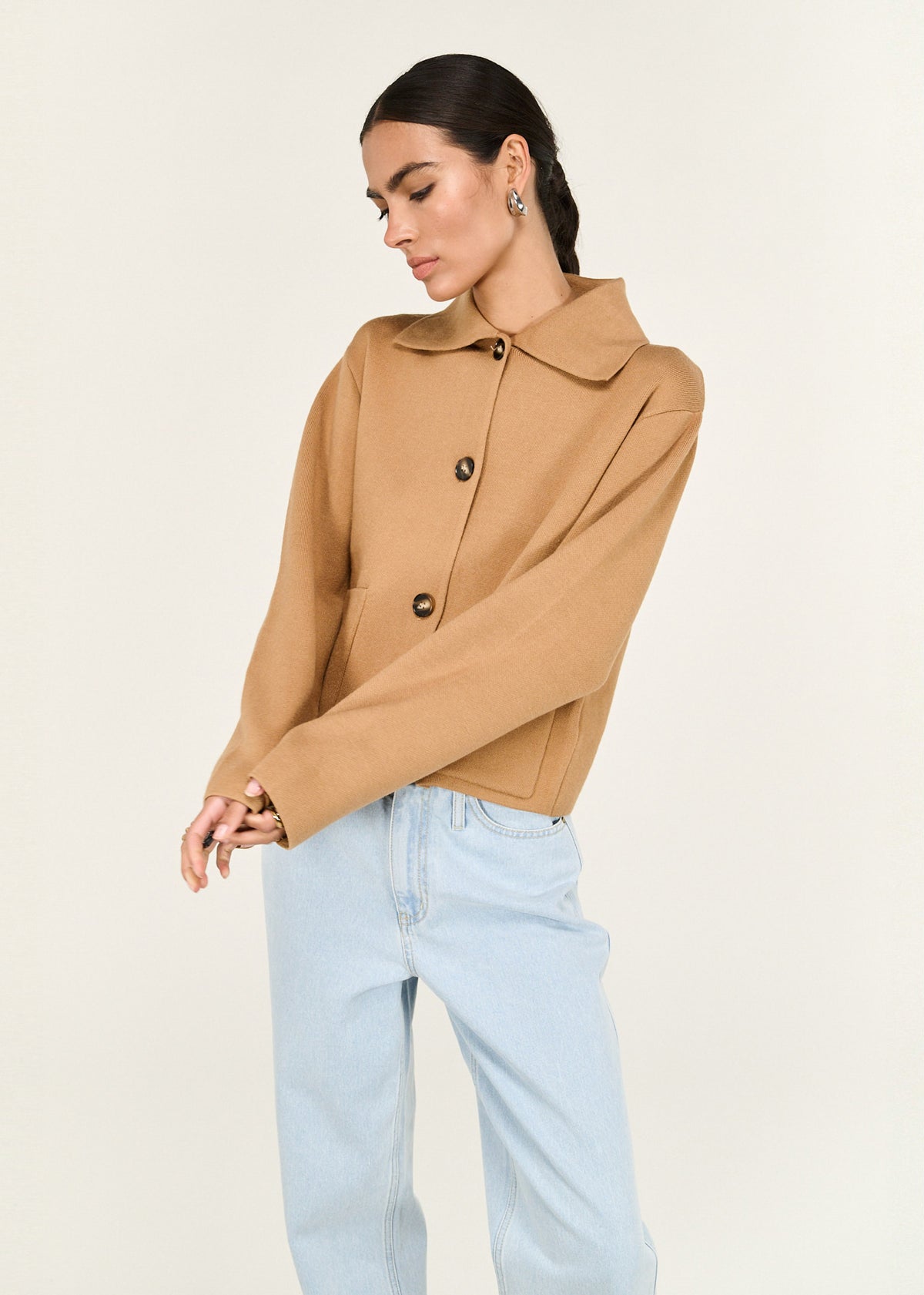 Model wearing Caramel Knitted Barn Jacket with a cropped silhouette and a relaxed fit, turned to the side.