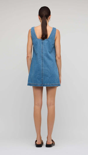 Back view of a woman wearing a Denim Square Neck Mini Dress, showcasing its relaxed A-line silhouette and structured neckline.
