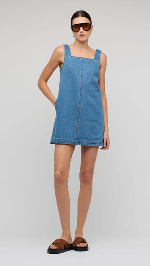 Denim Square Neck Mini Dress modeled by a woman wearing sunglasses and sandals against a neutral background.