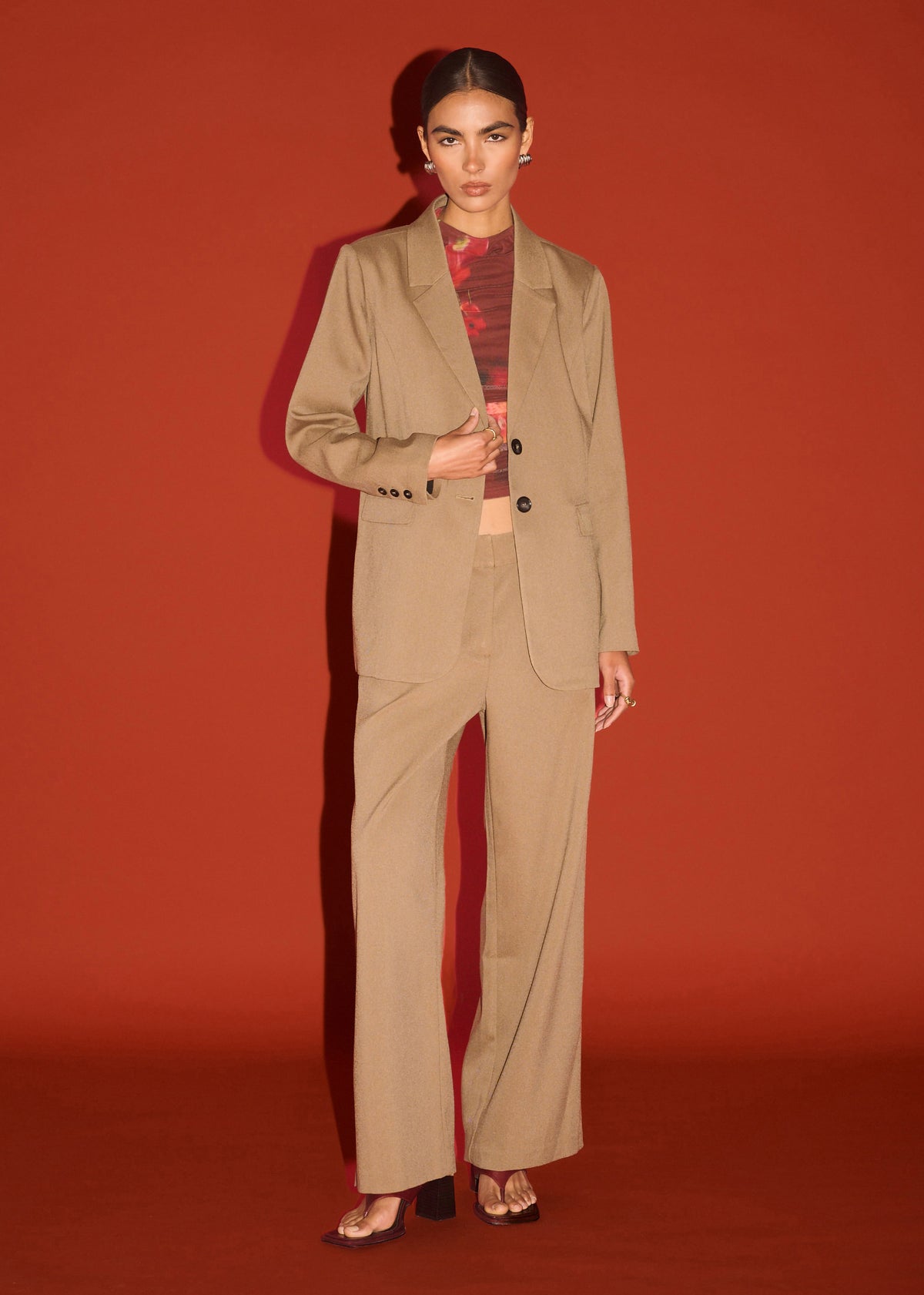 Model wearing Chai Relaxed Tailored Blazer with a single-breasted and notched lapels, photographed against a red studio backdrop.