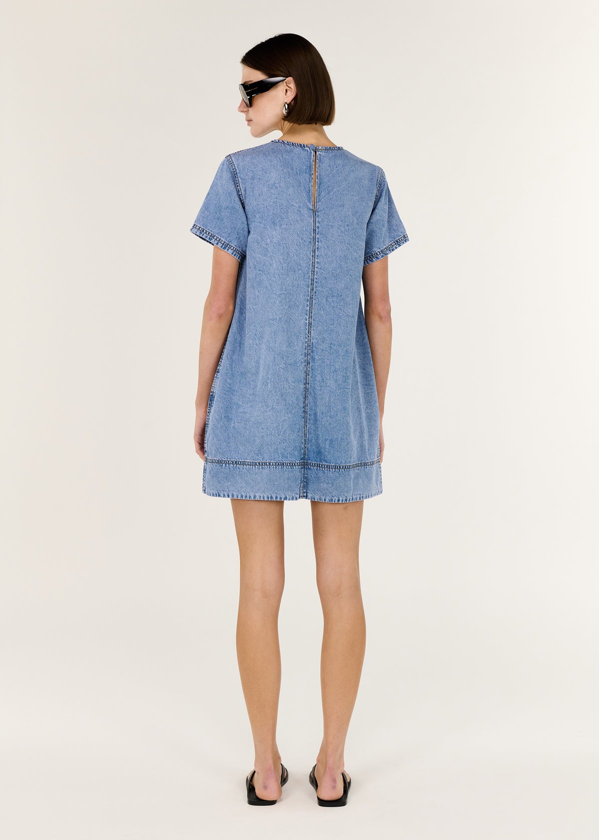 Back view of the Chambray Lightweight Mini Dress with a back keyhole with button closure and a relaxed A-line mini silhouette.