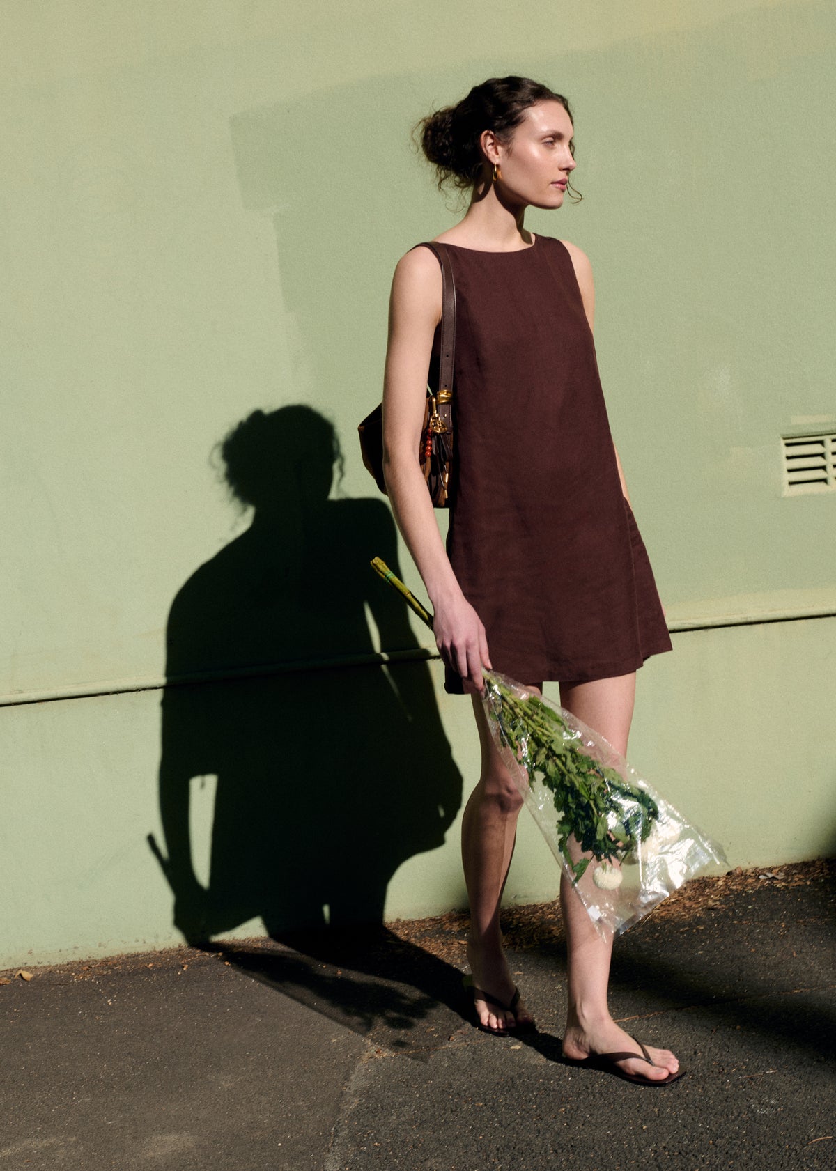 Model seated wearing Chocolate Linen Blend Boat Neck Mini Shift Dress with a v-back detail and a shift silhouette.