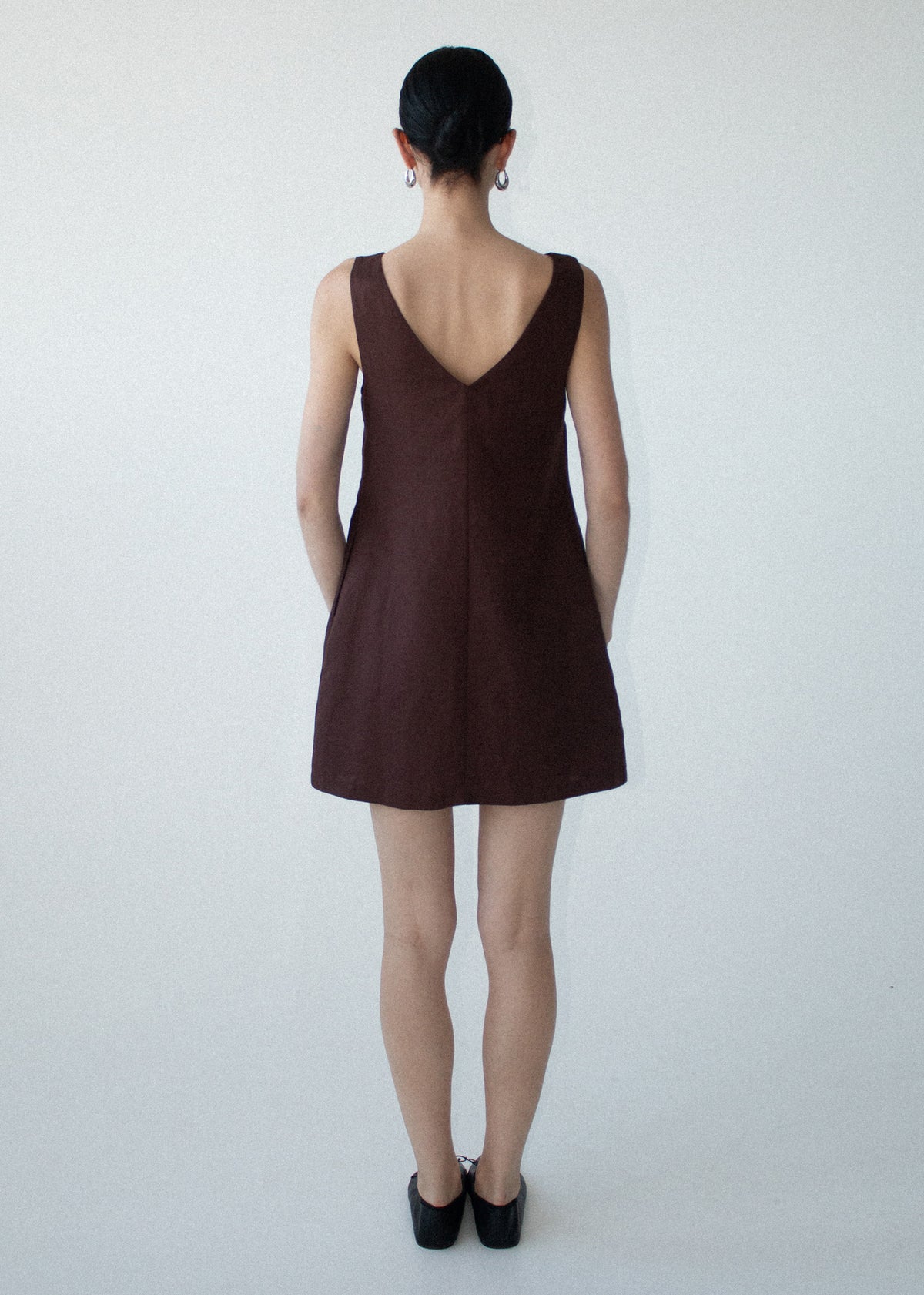 Back view of the Chocolate Linen Blend Boat Neck Mini Shift Dress with a v-back detail and a lightweight linen fabrication.