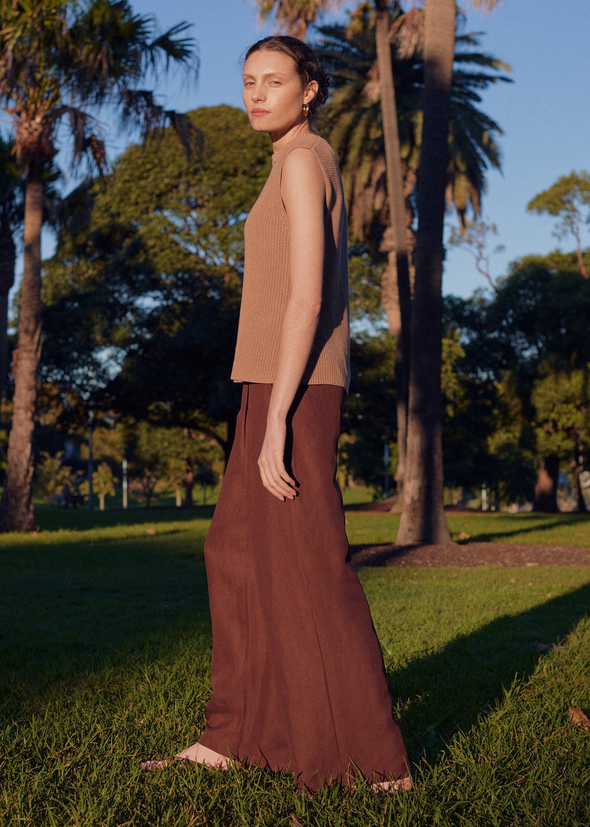 Model wearing Chocolate Linen Blend Wide Leg Tailored Pant with a button and zip fly closure, turned to the side.