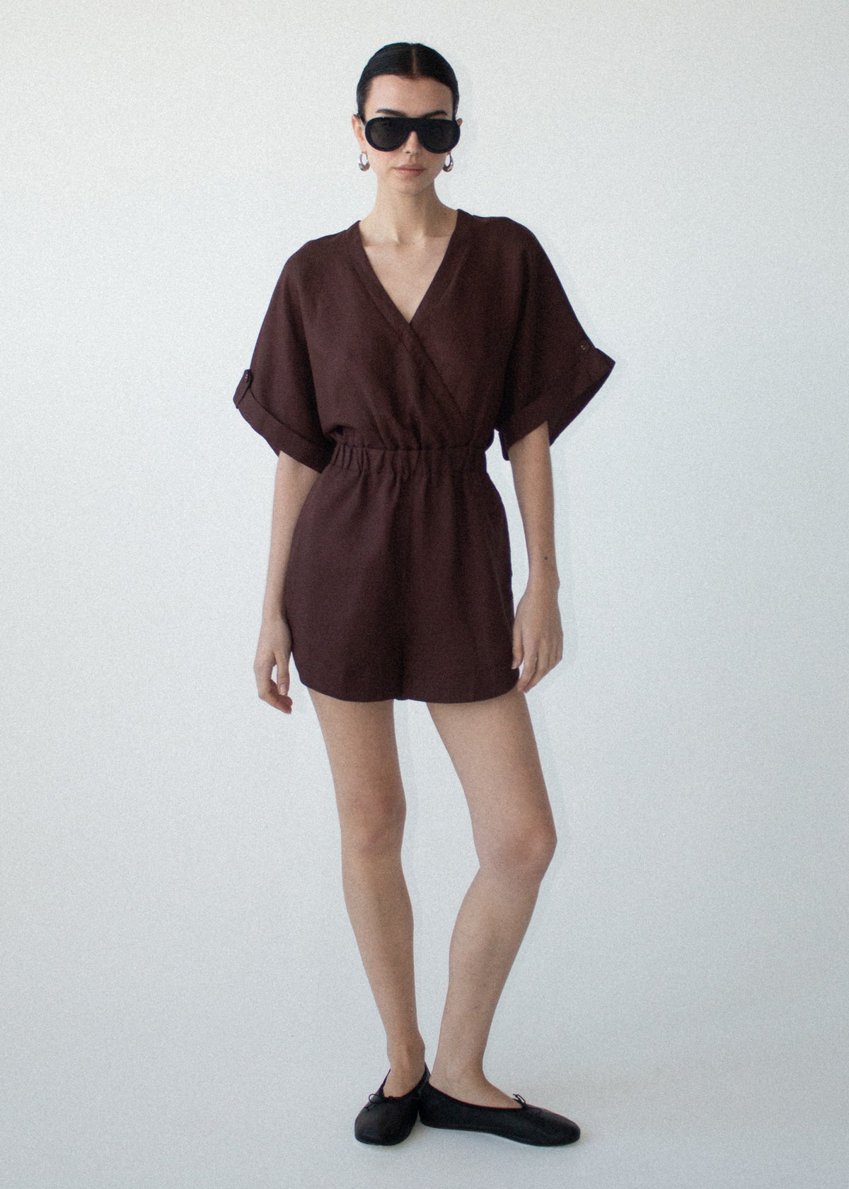 Model wearing Chocolate Linen Blend Wrap Playsuit, showing side pockets and a lightweight linen fabrication.
