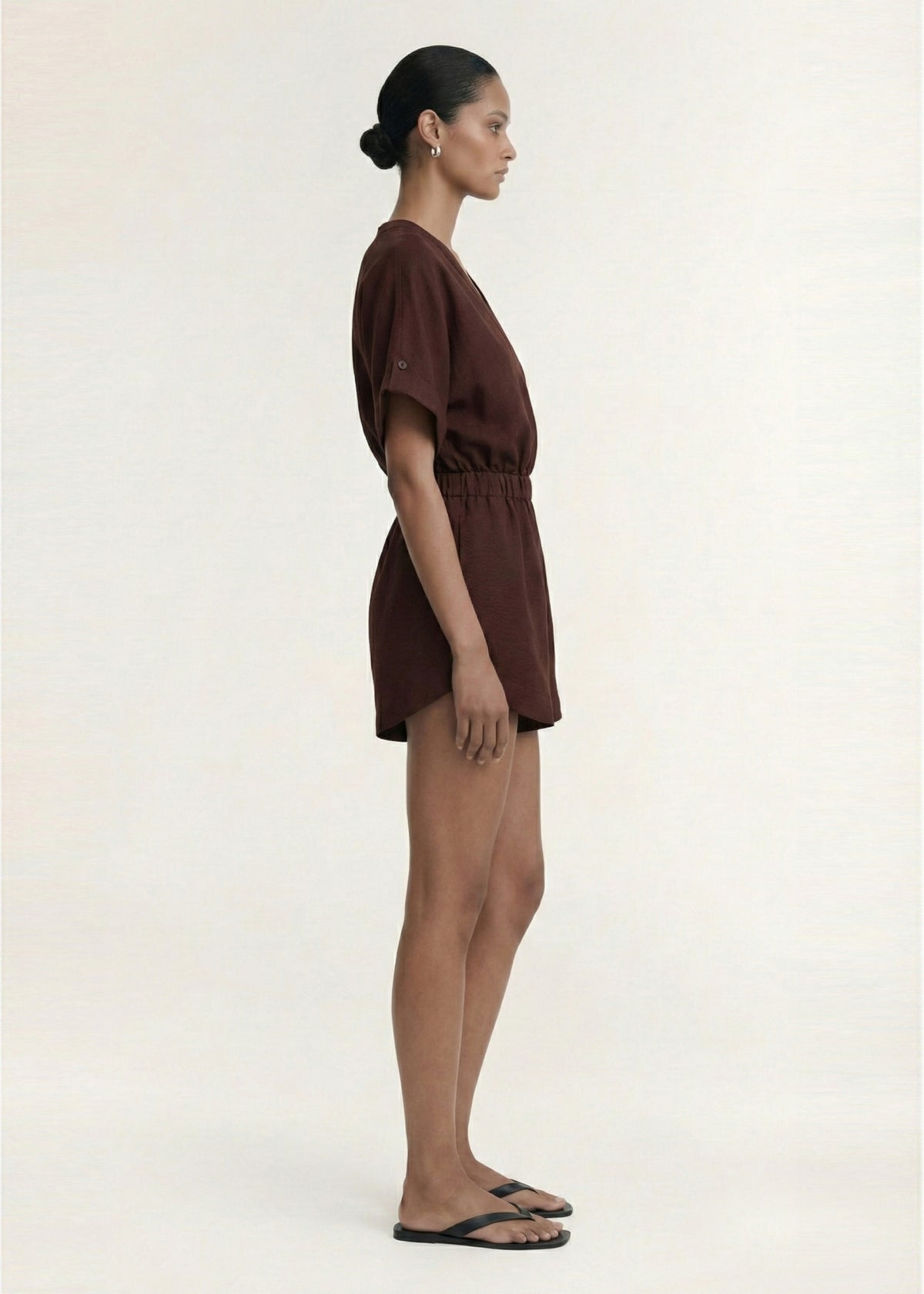 Side profile of the Chocolate Linen Blend Wrap Playsuit with a lightweight linen fabrication and a wrap-style V-neckline.