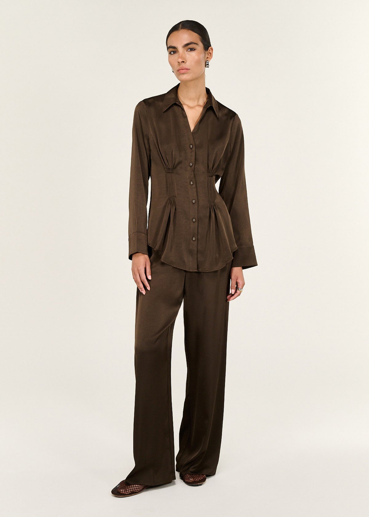 Model wearing Chocolate Pintuck Cinched Waist Satin Shirt, showing a pintuck cinched waist shaping and a subtle sheen.