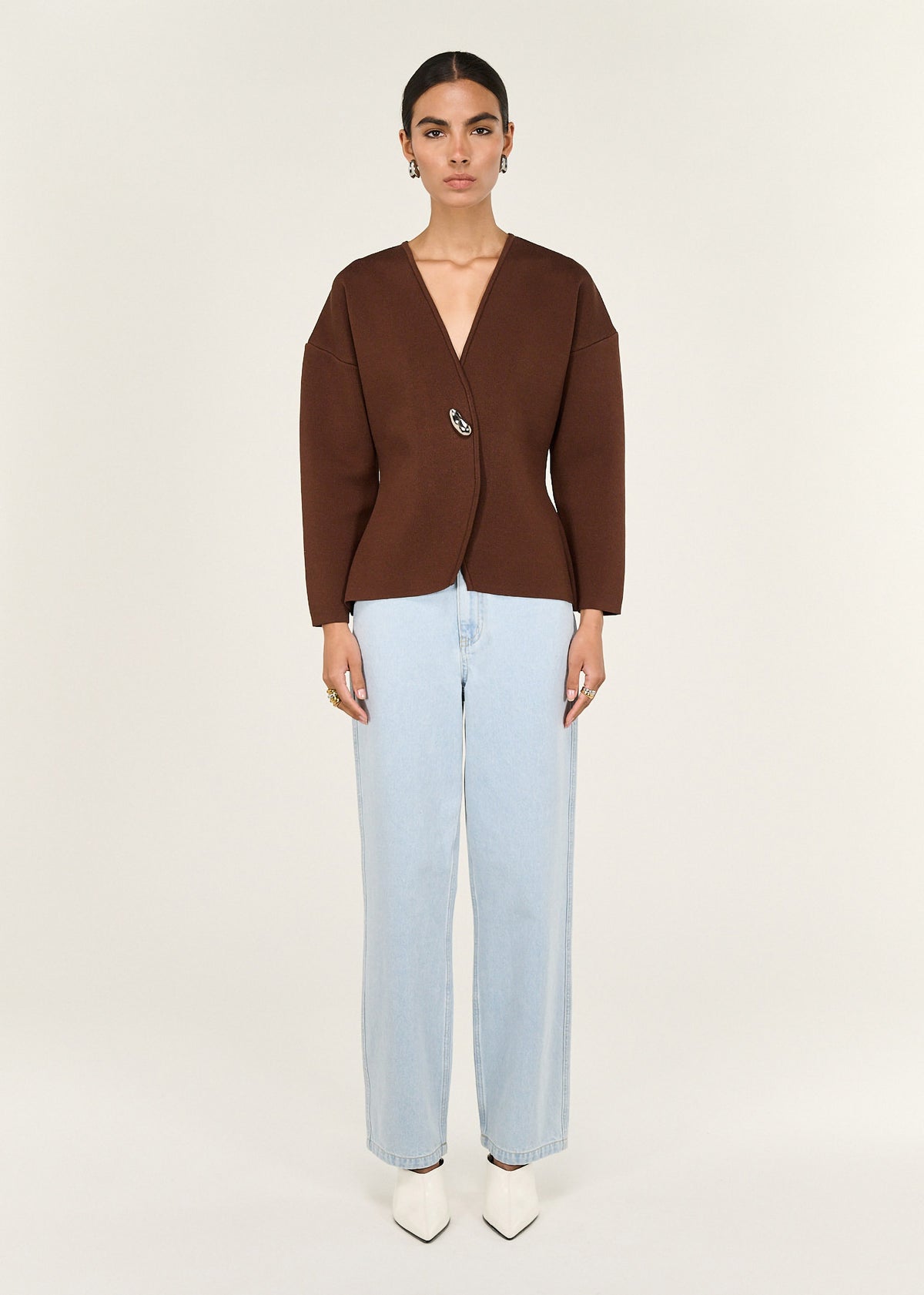 Model wearing Chocolate Sculptured Soft Cardigan with Hardware Detail with an asymmetrical button closure and a deep V neckline.