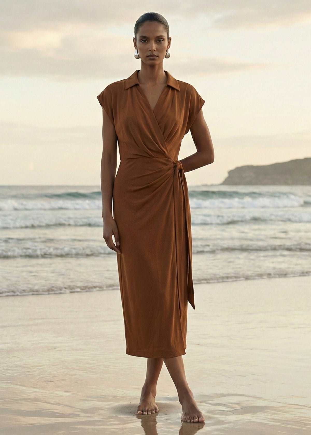 Model wearing Copper Draped Wrap Midi Dress with extended shoulder sleeves and a wrap front with self-tie waist, turned to the side.