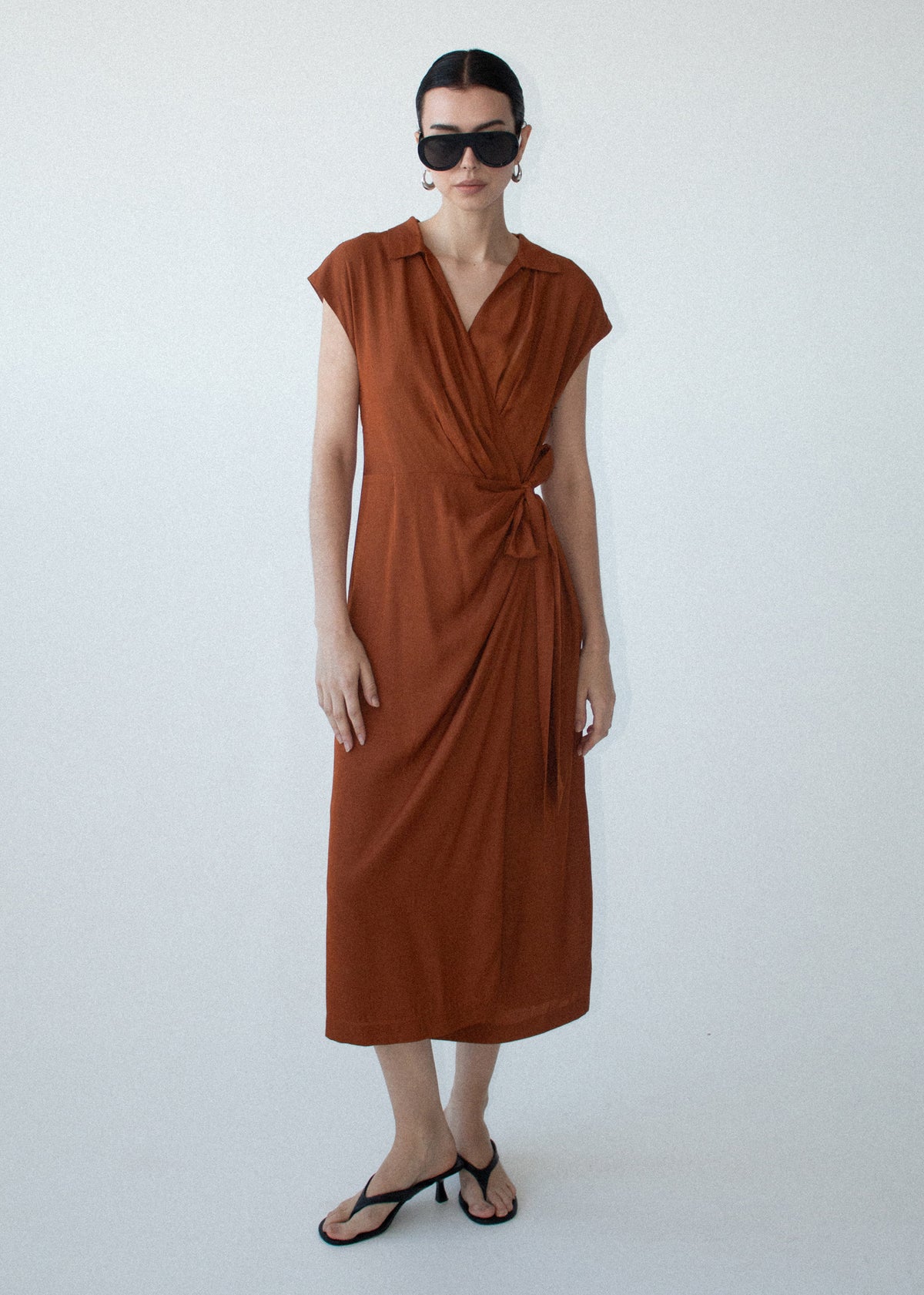 Model wearing Copper Draped Wrap Midi Dress, showing a gathered waist detailing and a front split.