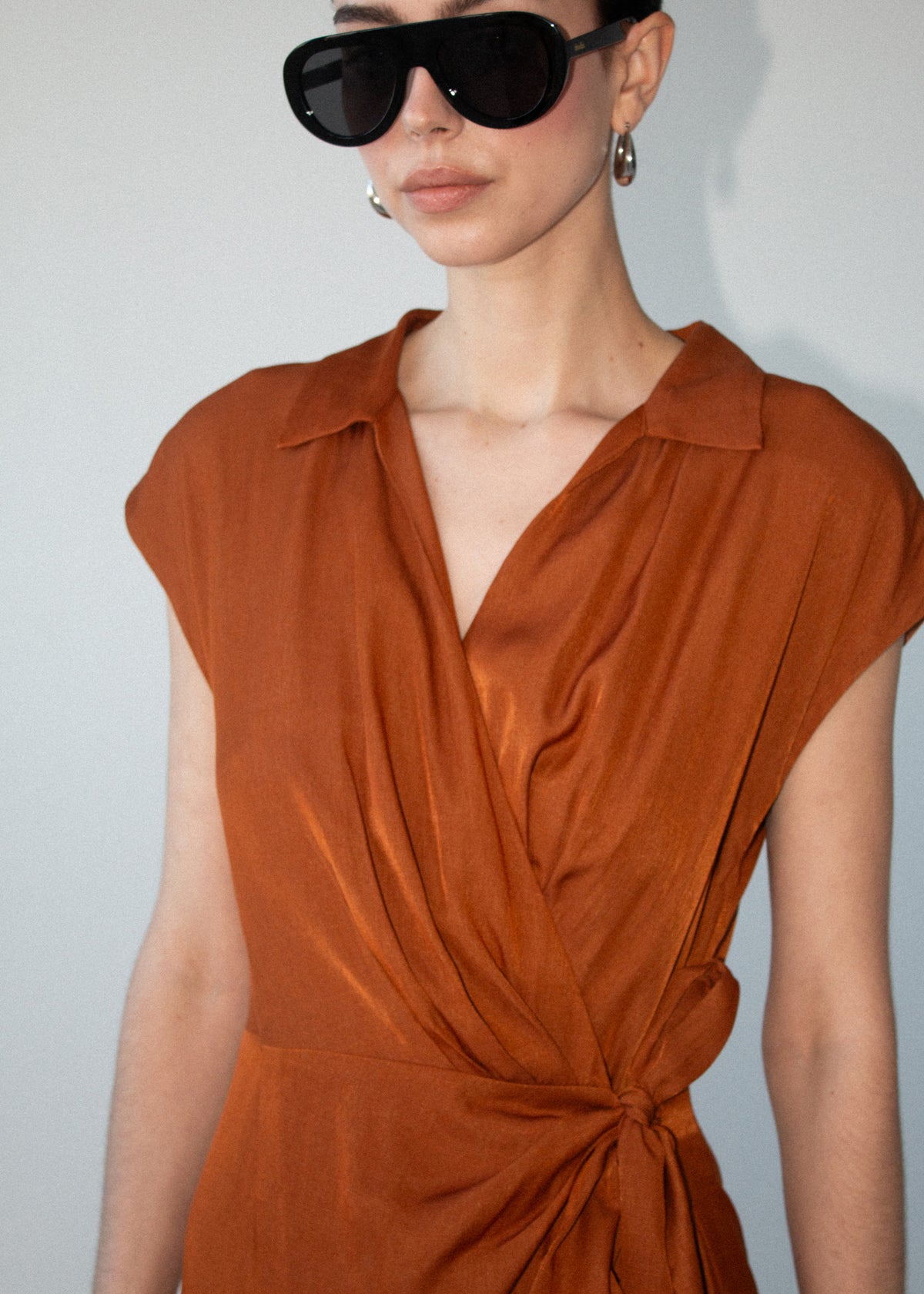 Close-up detail of the Copper Draped Wrap Midi Dress, showing draped neckline.