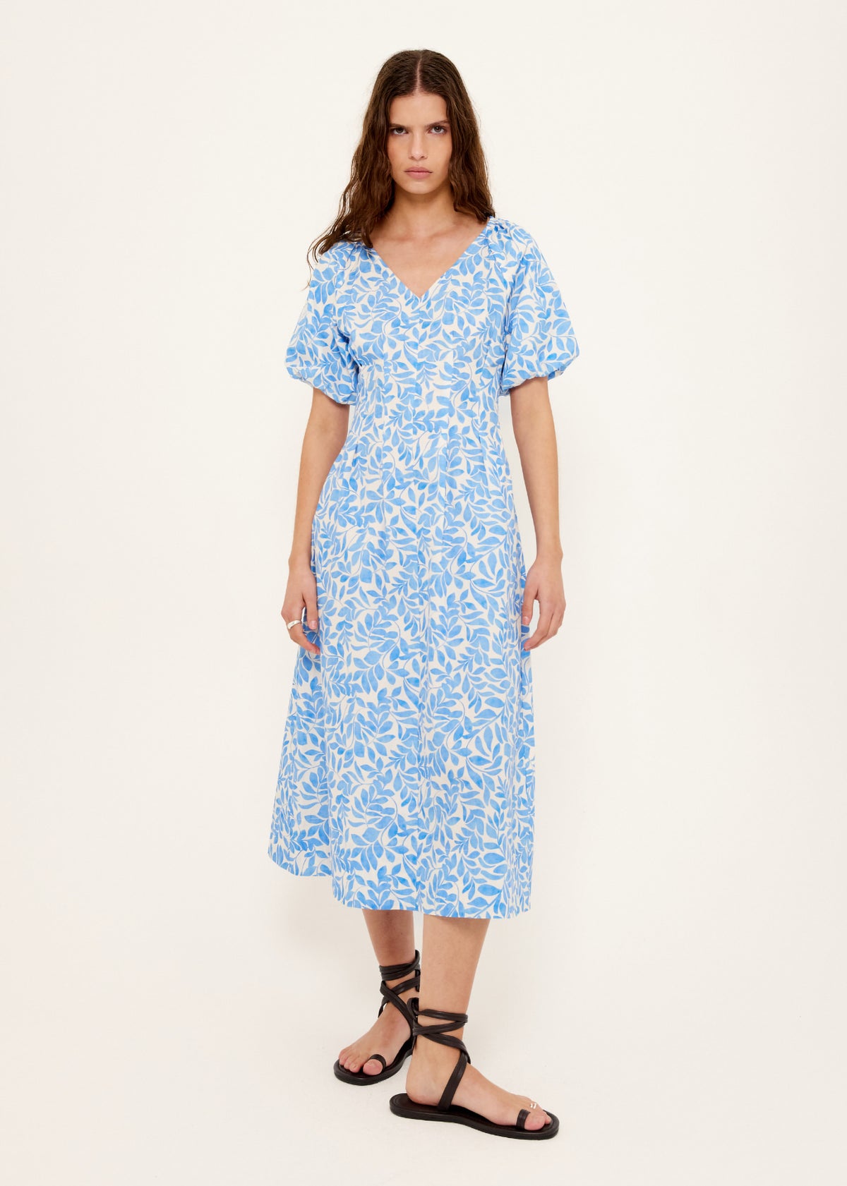 Model wearing Cotton Blue Leaf Print V-neck Midi Dress with a short puff sleeves with elastic cuff and a v-neckline with gathered bust seam.