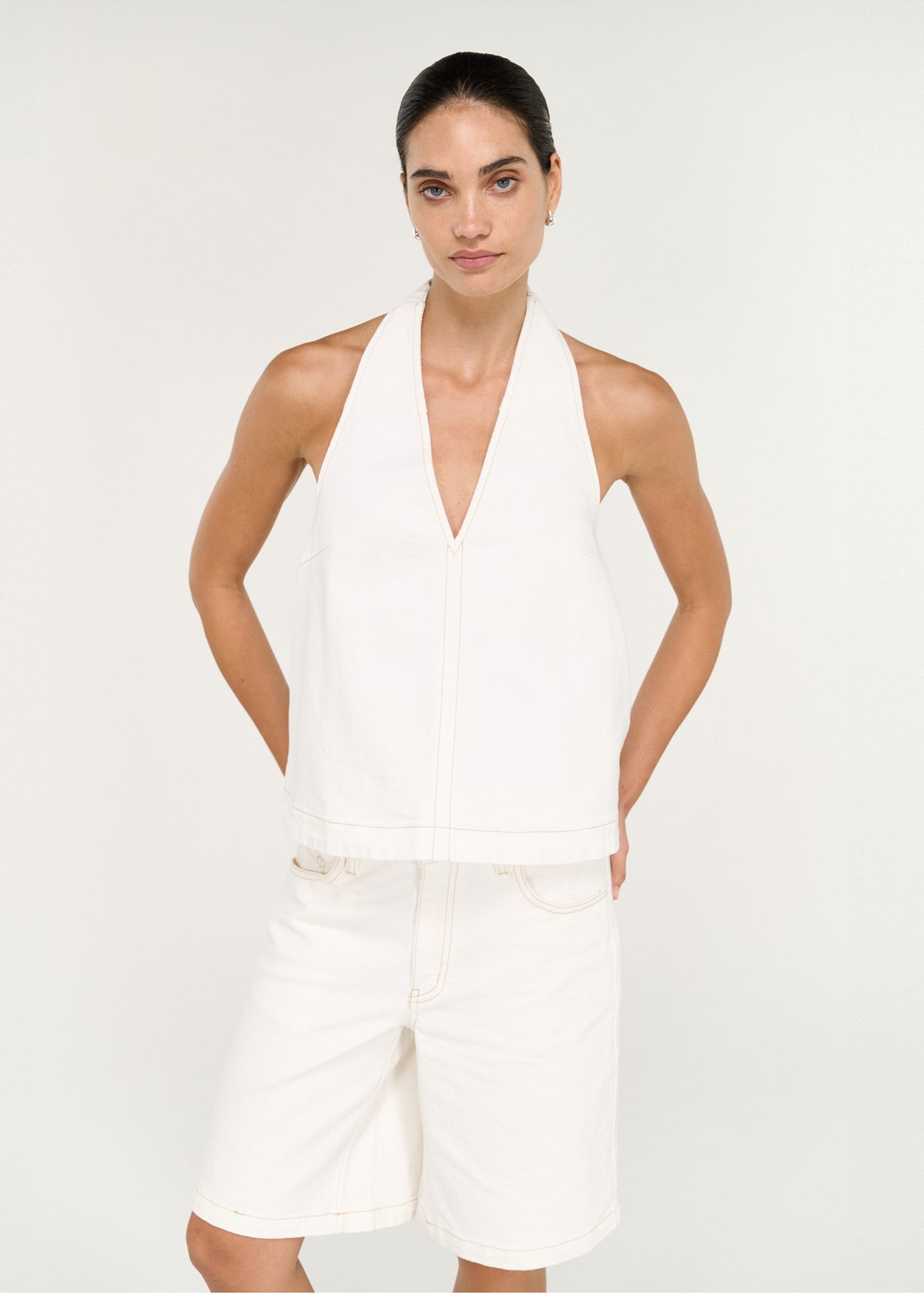 Model wearing Cotton Denim Halter Top in White with a structured denim fabrication and a relaxed A-line silhouette.
