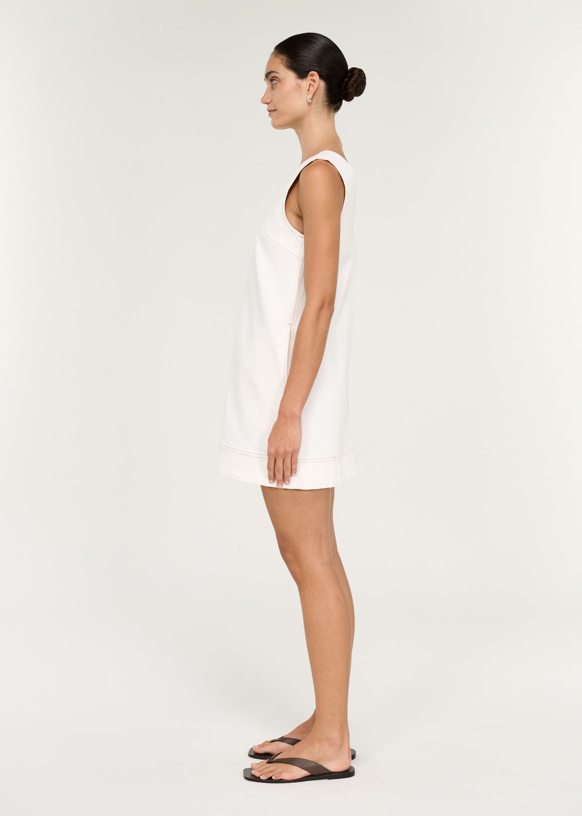 Side view of the Cotton Denim Mini Shift Dress in White, showing a structured denim fabrication and a relaxed shift silhouette.