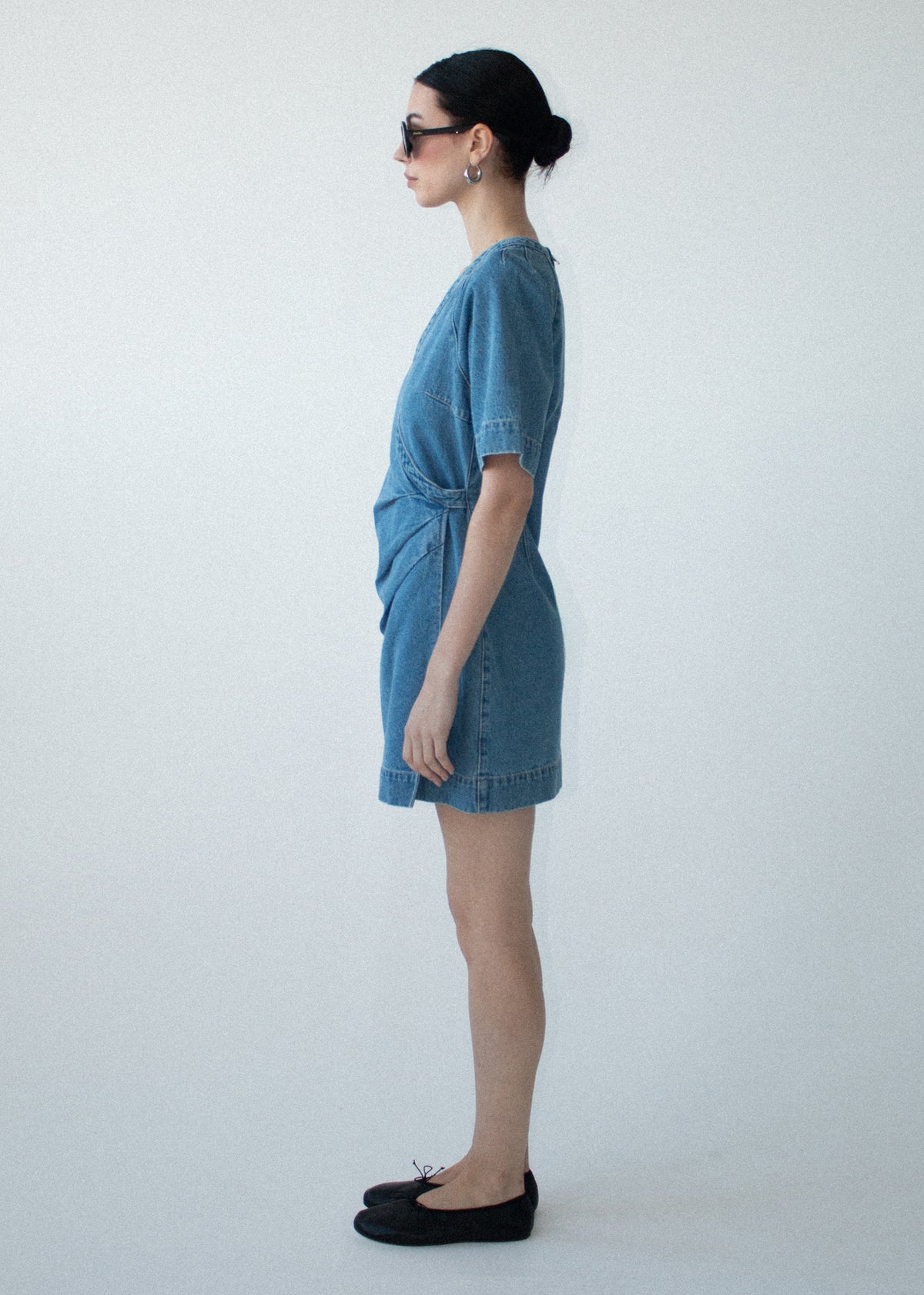 Side view of the Cotton Denim Wrap Detail Mini Dress, showing short sleeves and a pleat detailing through waist.