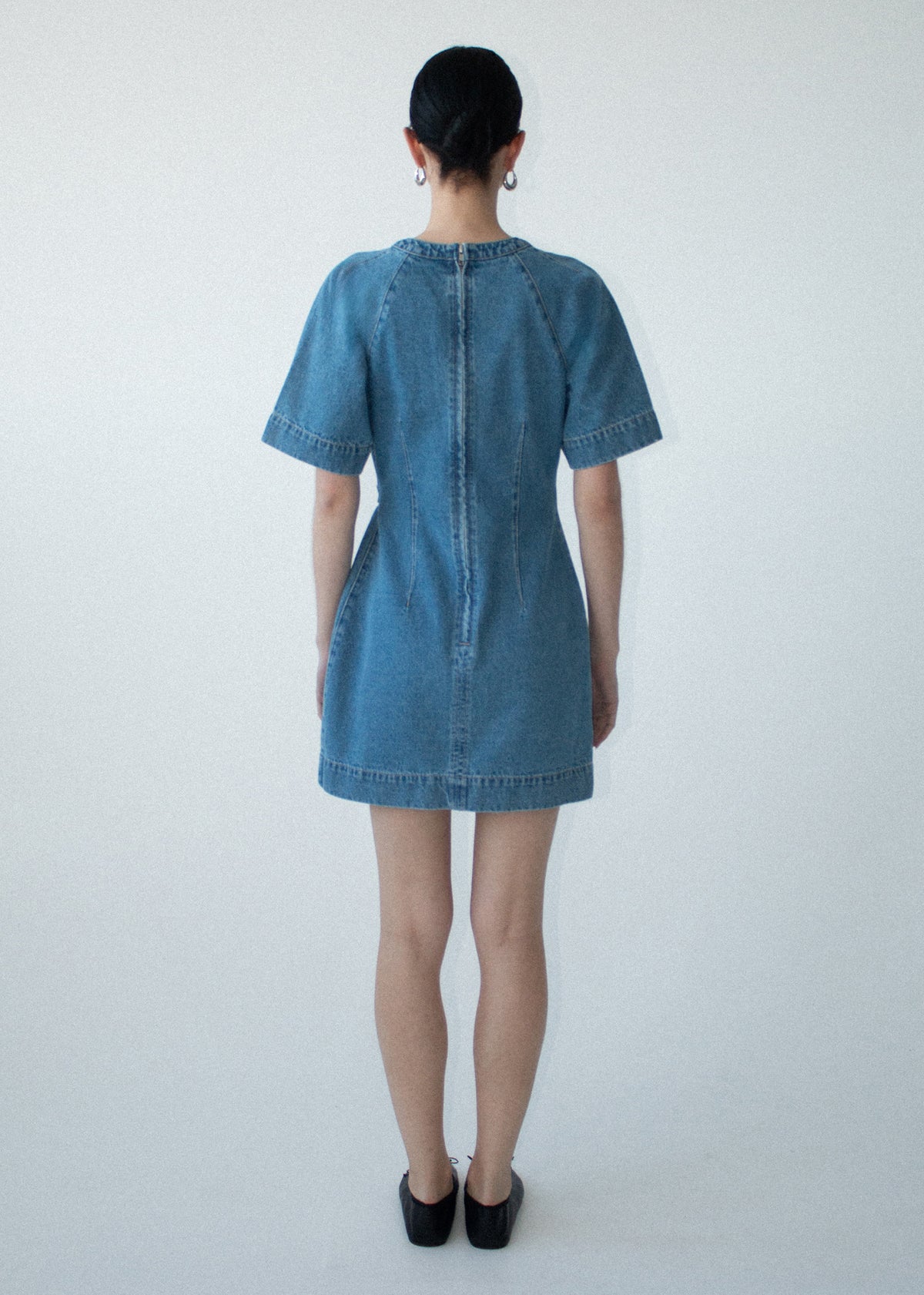 Back view of the Cotton Denim Wrap Detail Mini Dress with a back zip closure and a soft mid-wash denim fabrication.