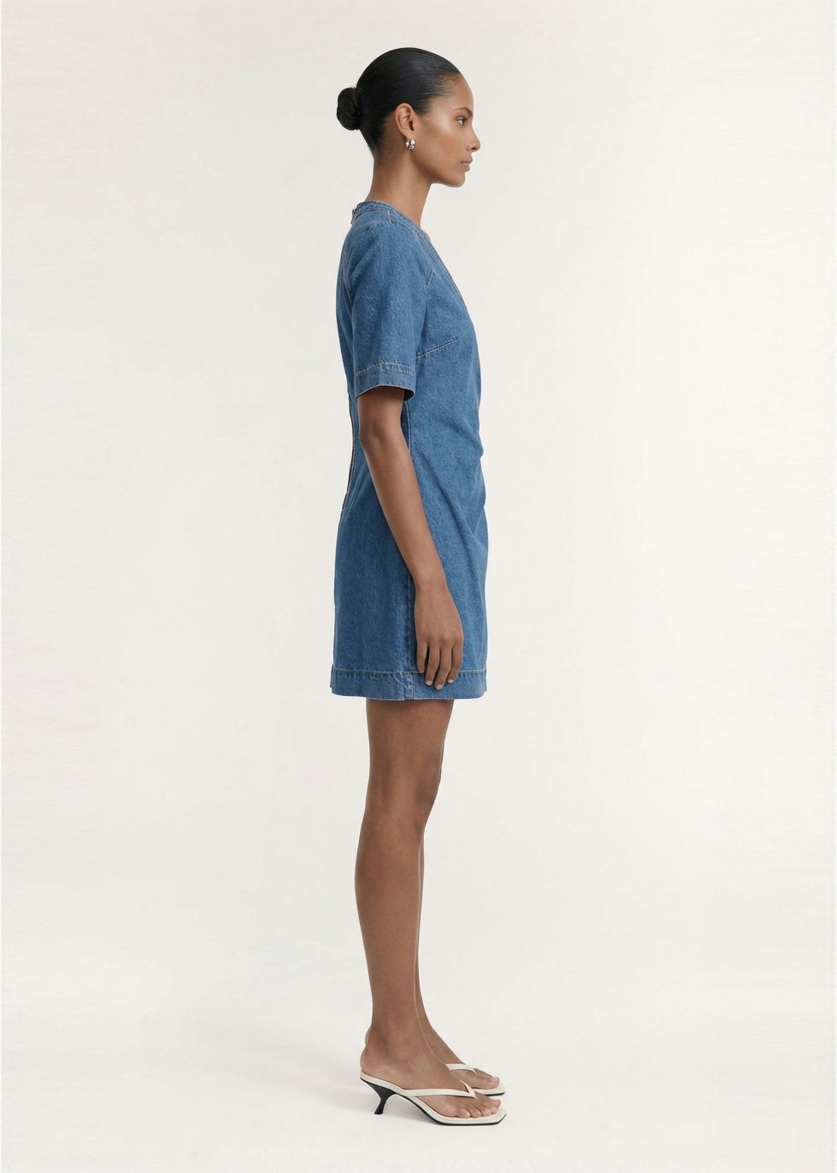 Side profile of the Cotton Denim Wrap Detail Mini Dress with a wrap-style bodice detail and a mini length silhouette.