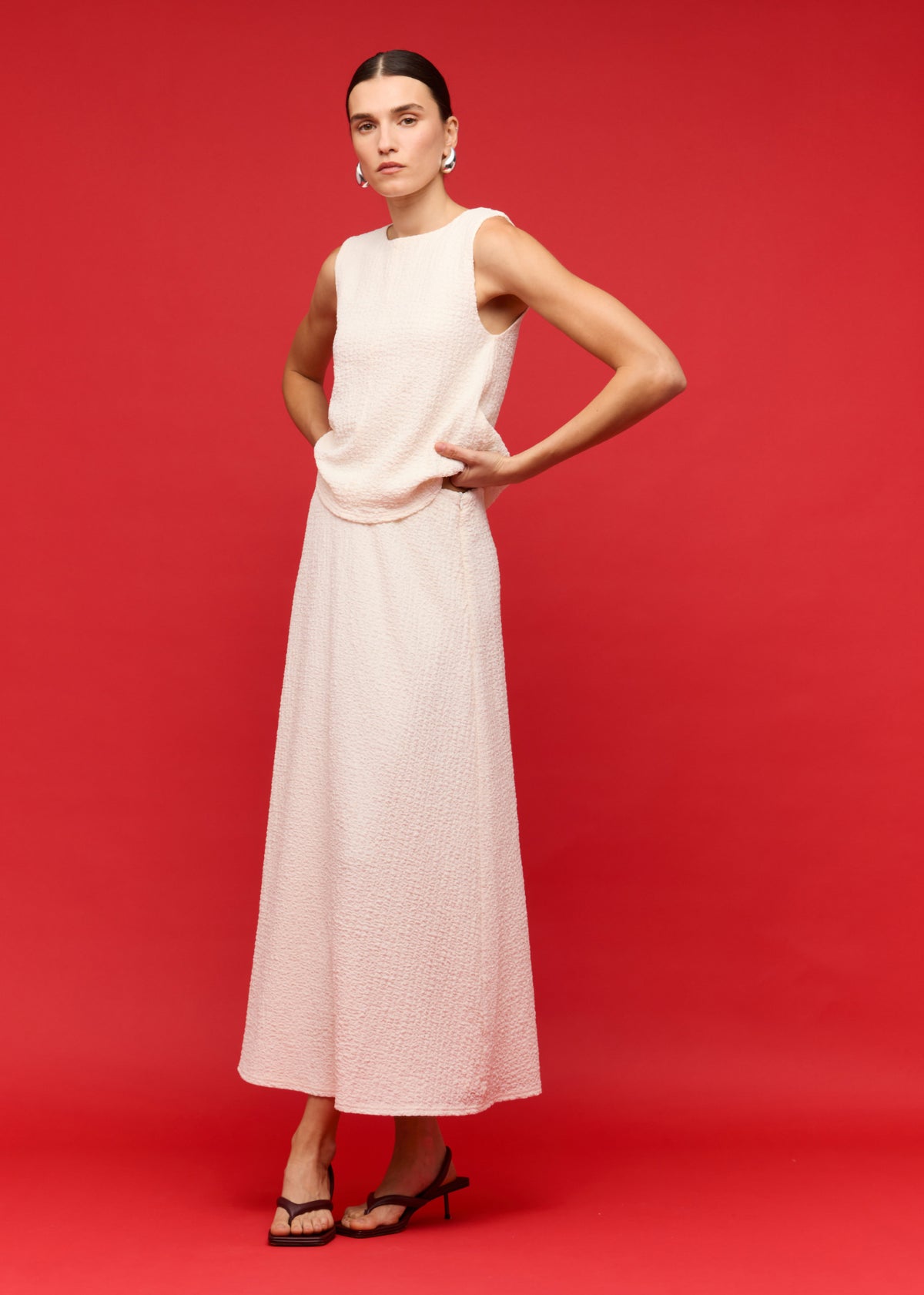 Model wearing Cream A-Line Midi Skirt with a midi length, photographed against a red studio backdrop.