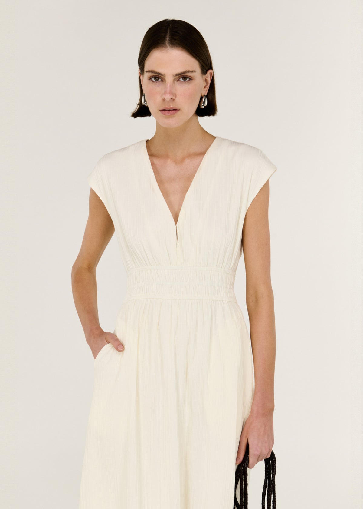Close-up of the Cream Cotton V-Neck Midi Dress, showing soft cap sleeves and a defined waist with gentle gathering.