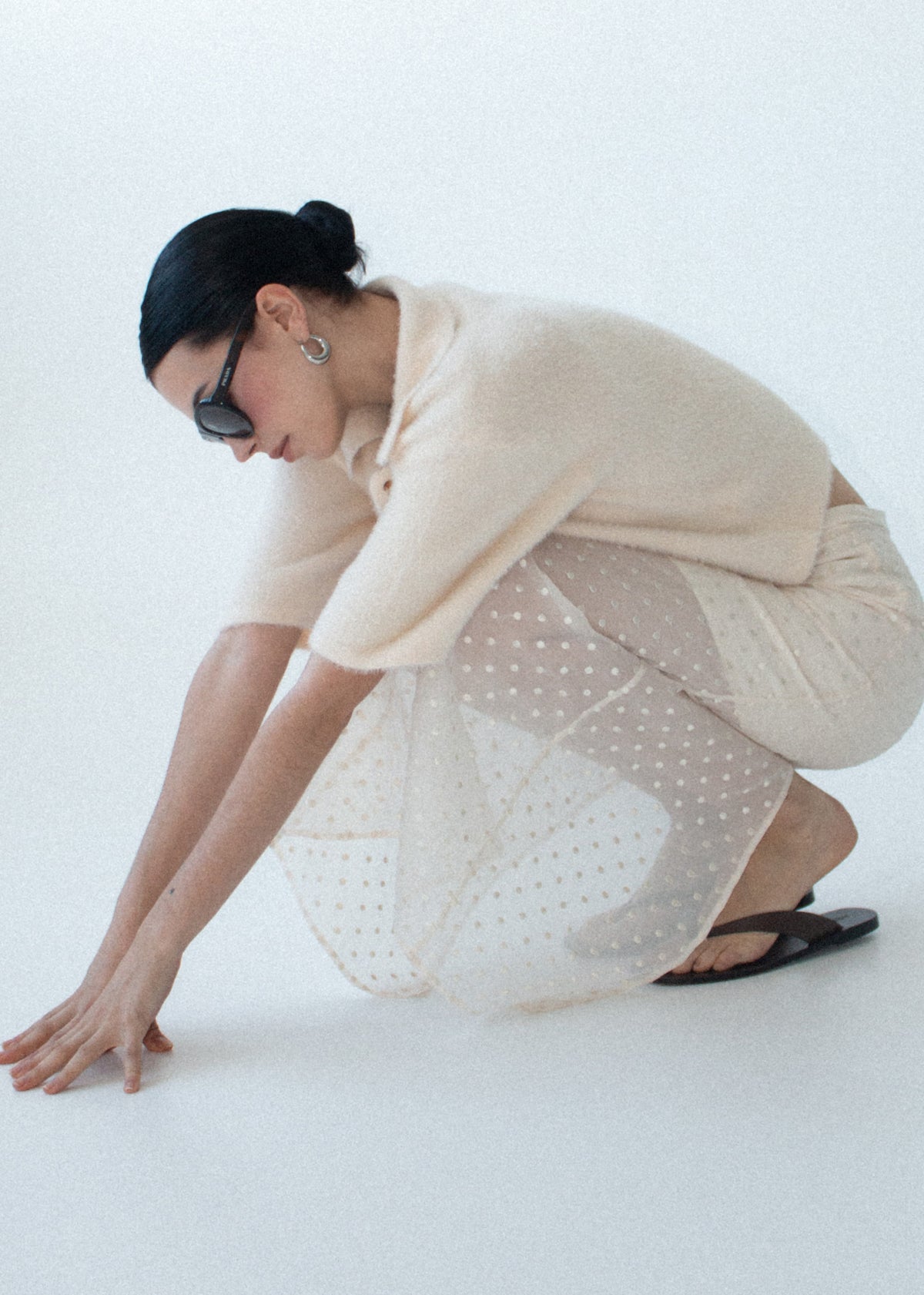 Model seated wearing Cream Embroidered Spot Sheer Layered Midi Skirt with a fitted silhouette and a natural waist.