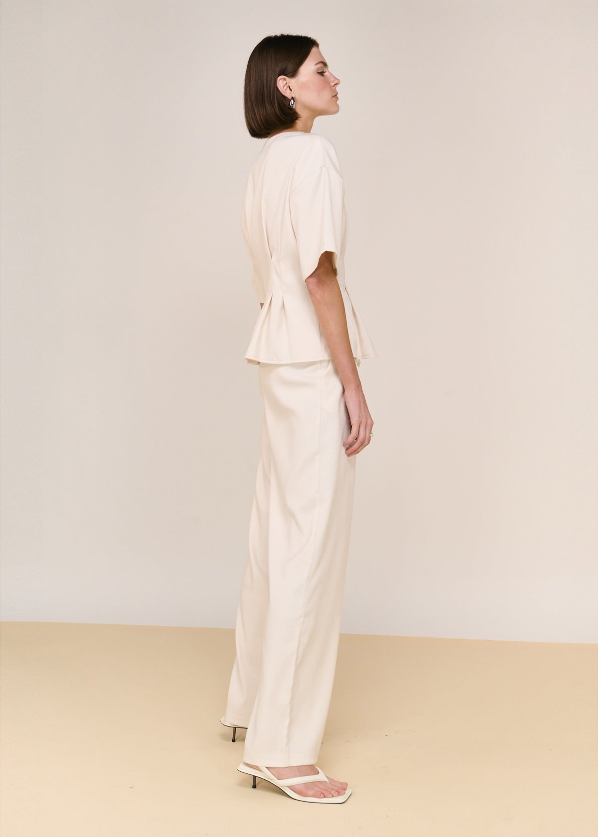 Side view of the Cream High Waisted Drape Pant, showing functional side pockets and a high-waisted fit.