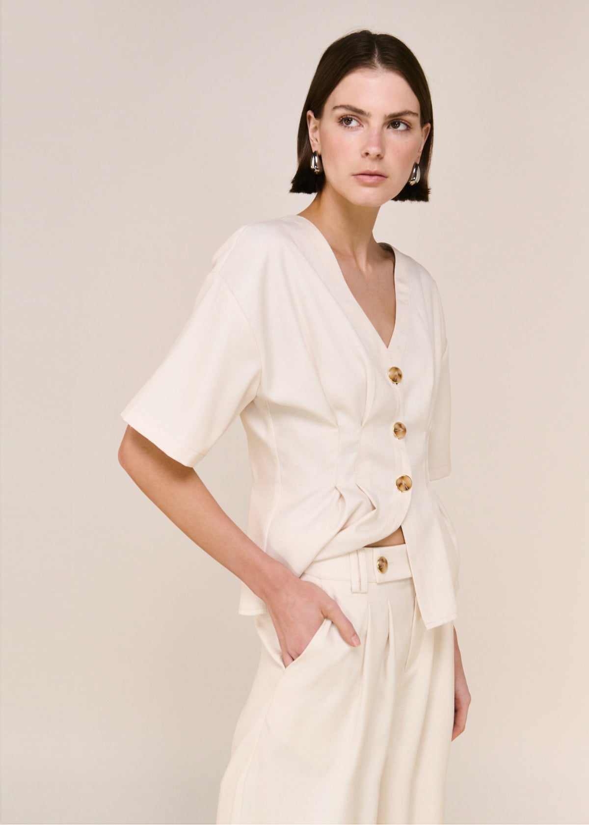 Close-up of the Cream Pintuck Button Front Top, showing a v-neckline and a statement button detailing.