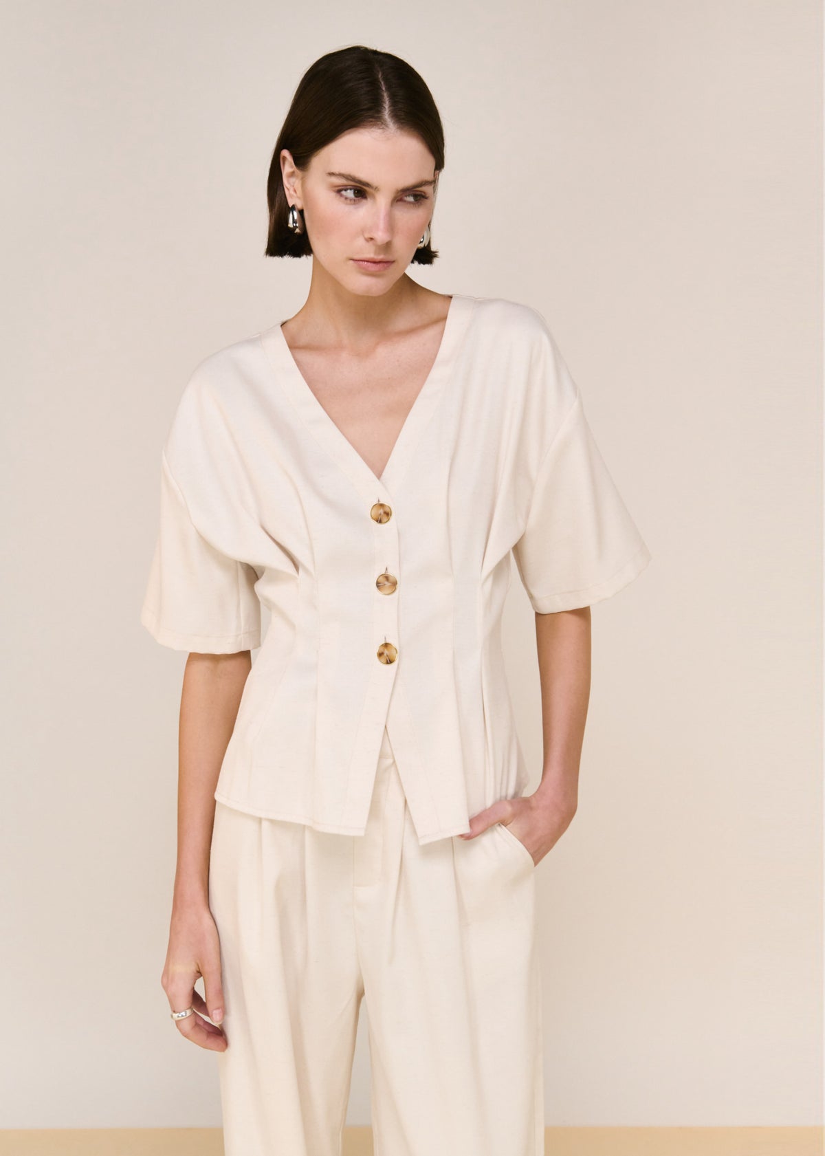 Close-up of Cream Pintuck Button Front Top with a v-neckline and a statement button detailing.