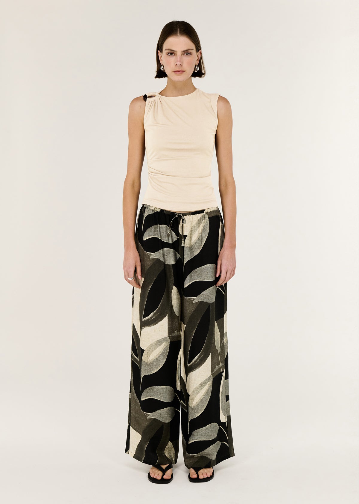 Model wearing Cream Ruched Slinky Tank with a sleeveless silhouette and a shoulder hardware detail.